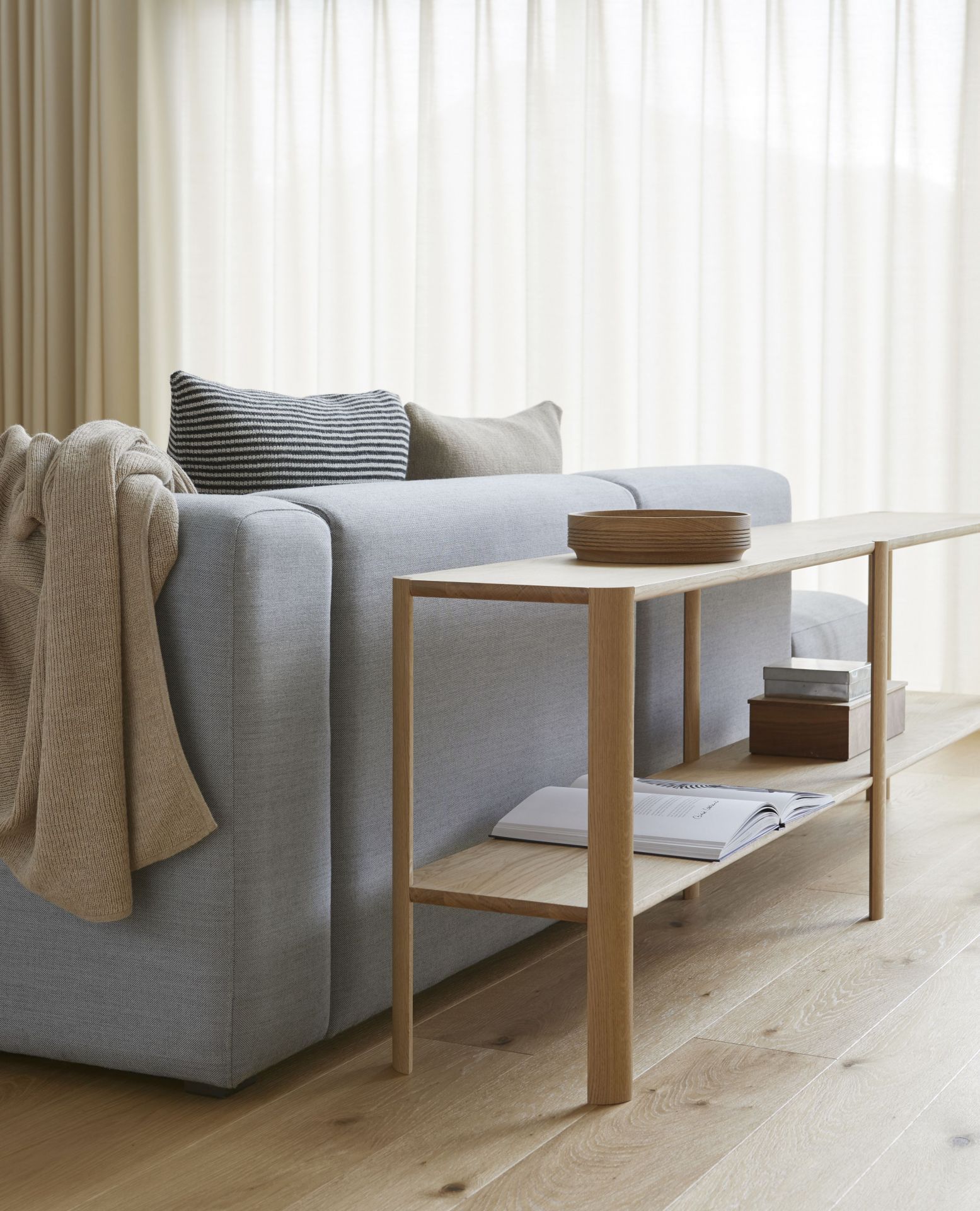 Leaf Regal 2x2 von Form & Refine aus Eiche, weiß geölt, neben einem Sofa.