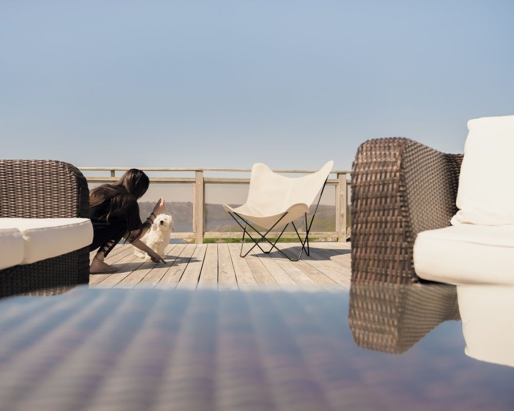 Mariposa Butterfly Chair Sessel Cuero auf Holzterrasse mit Frau und Hund. Outdoor Möbel.
