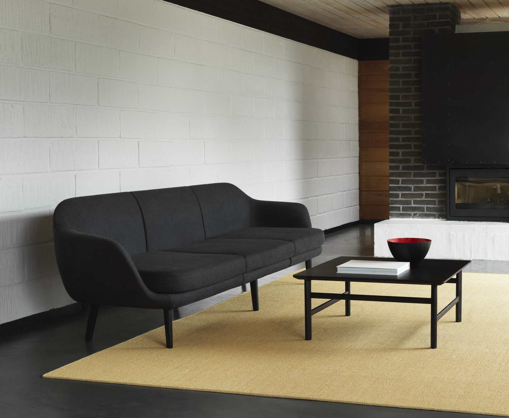 Schwarzer Grow Table Couchtisch von Normann Copenhagen vor Sofa und Kamin. Moderner Wohnzimmertisch.