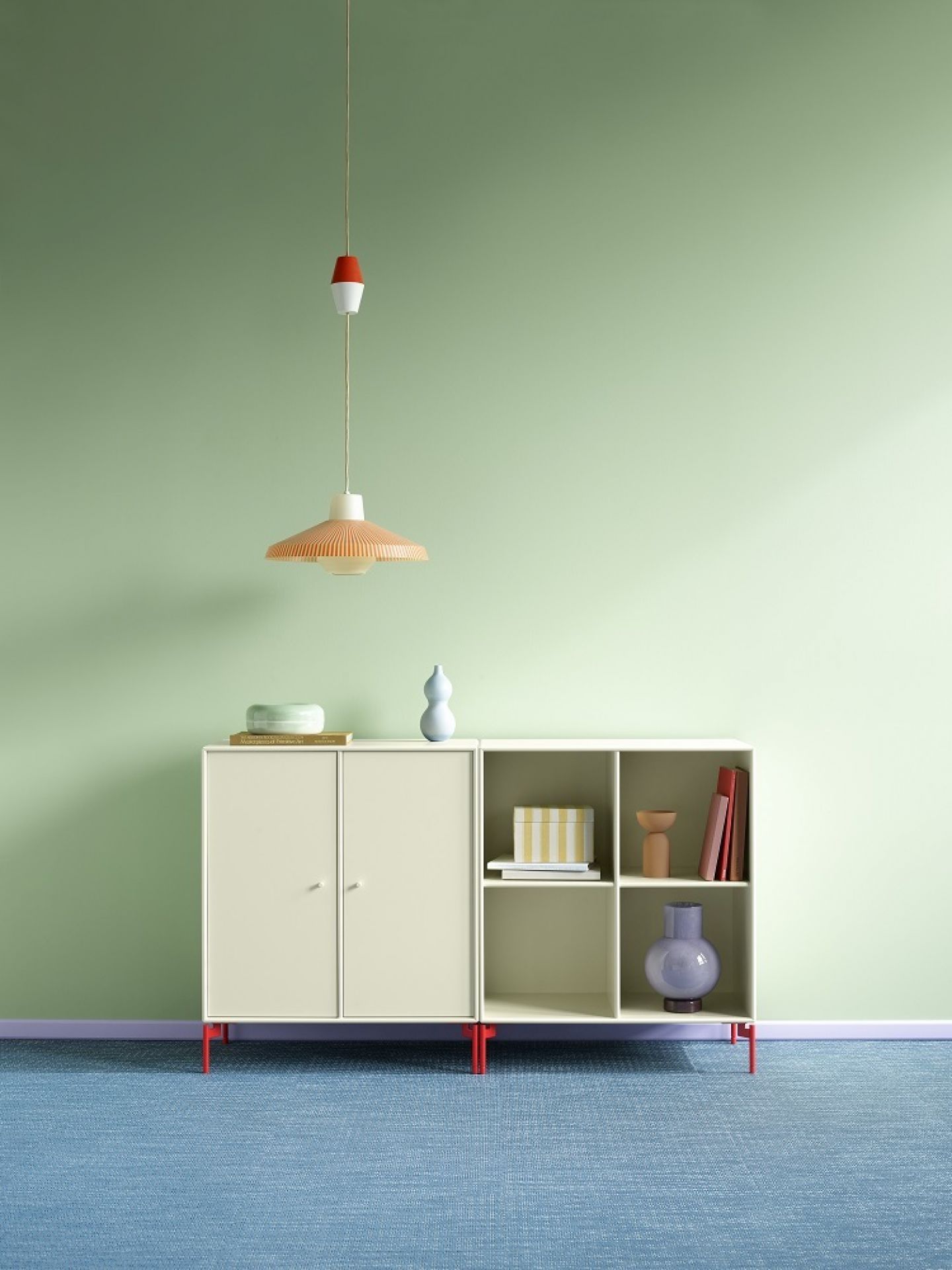 Weißes Montana Pair Sideboard mit Fächern und Türen, kombiniert mit Deko-Elementen, vor hellgrünem Hintergrund.