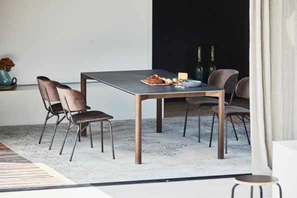 Radius Tisch von Jan Kurtz mit dunkler Tischplatte und Holzgestell, umgeben von Stühlen.