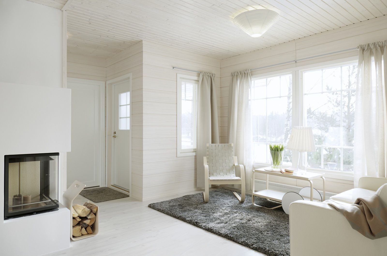 Heller Wohnraum mit Armchair 406 Sessel von Artek, Design-Klassiker aus Holz und Stoff.