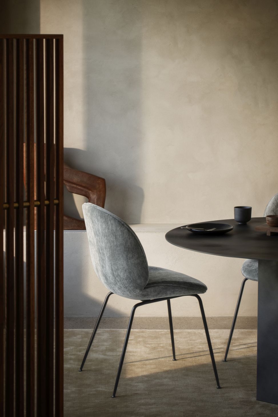 Detailaufnahme: Runder Esstisch von Gubi mit Stahlfuß und grauen Stühlen. Modernes Esszimmer Design.