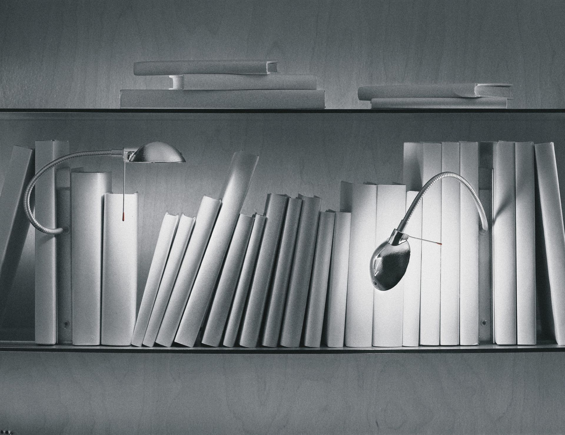 Silberne Oskar Regalleuchte von Ingo Maurer zwischen weißen Büchern im Regal. Designleuchte für Bücherregale.