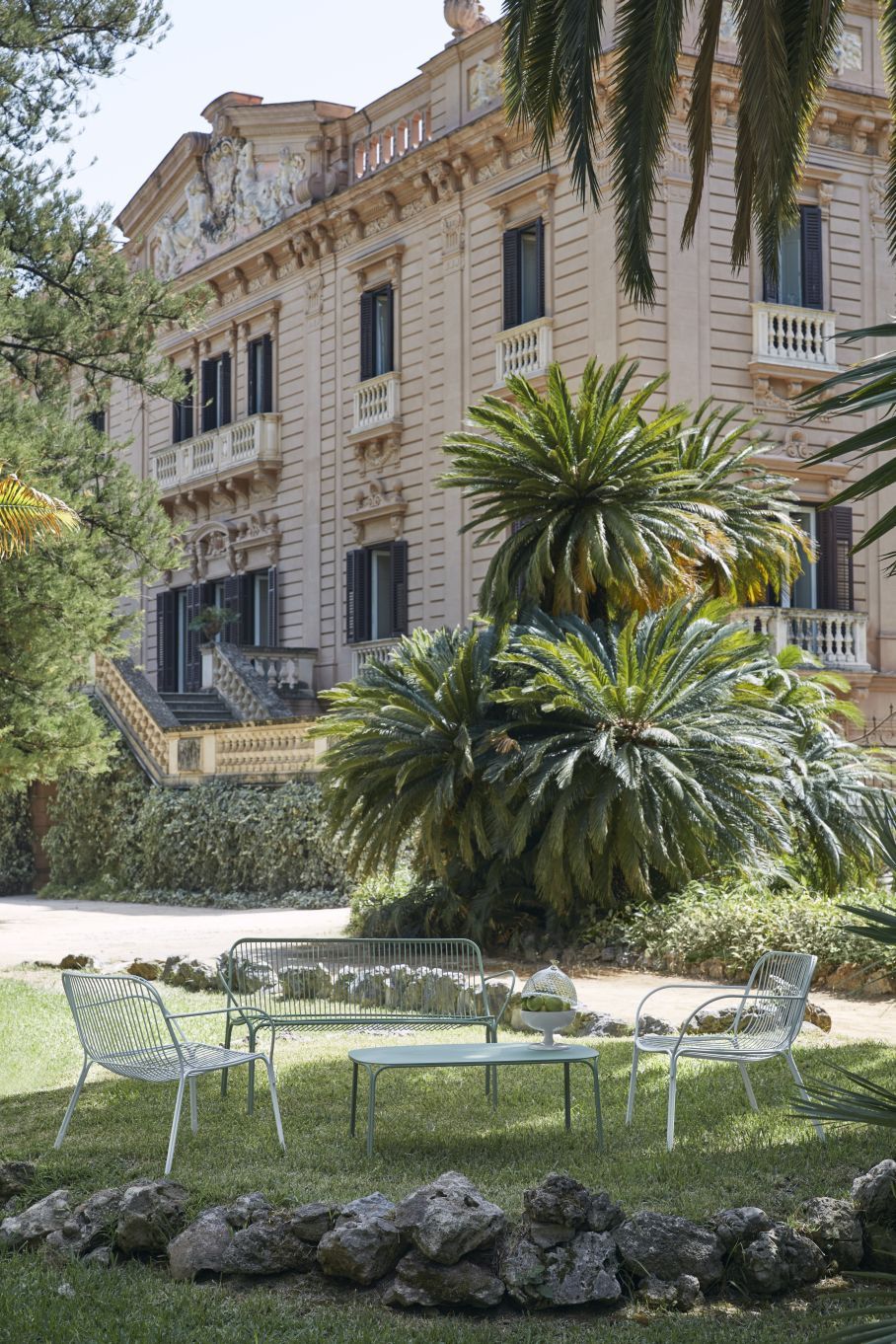 Hiray Outdoor Kaffeetisch von Kartell, hellgrün, mit Stühlen und Bank im Garten.