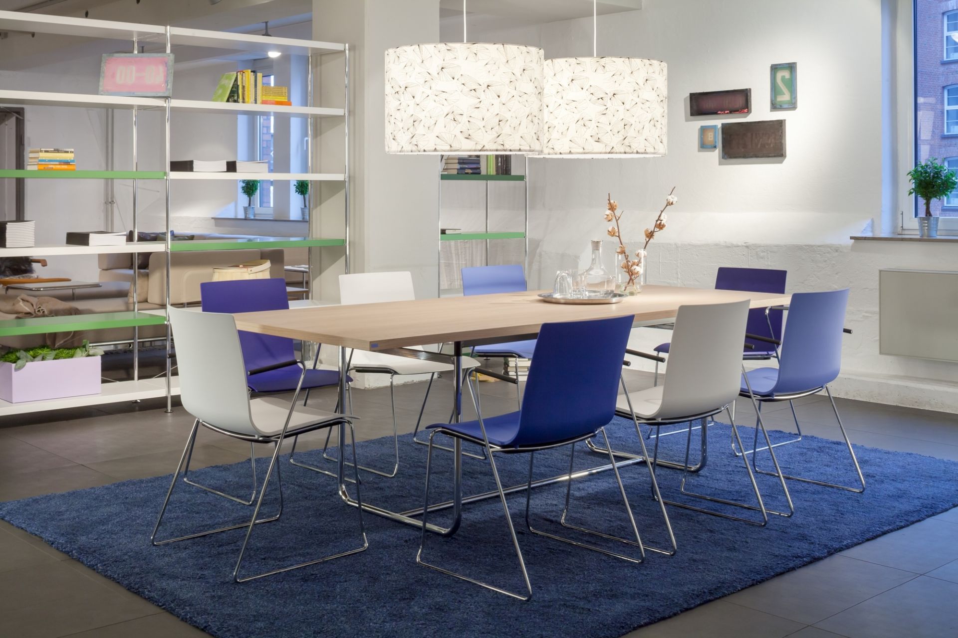 Moderner S 1070 Thonet Esstisch aus Holz mit blauen und weißen Stühlen auf blauem Teppich.