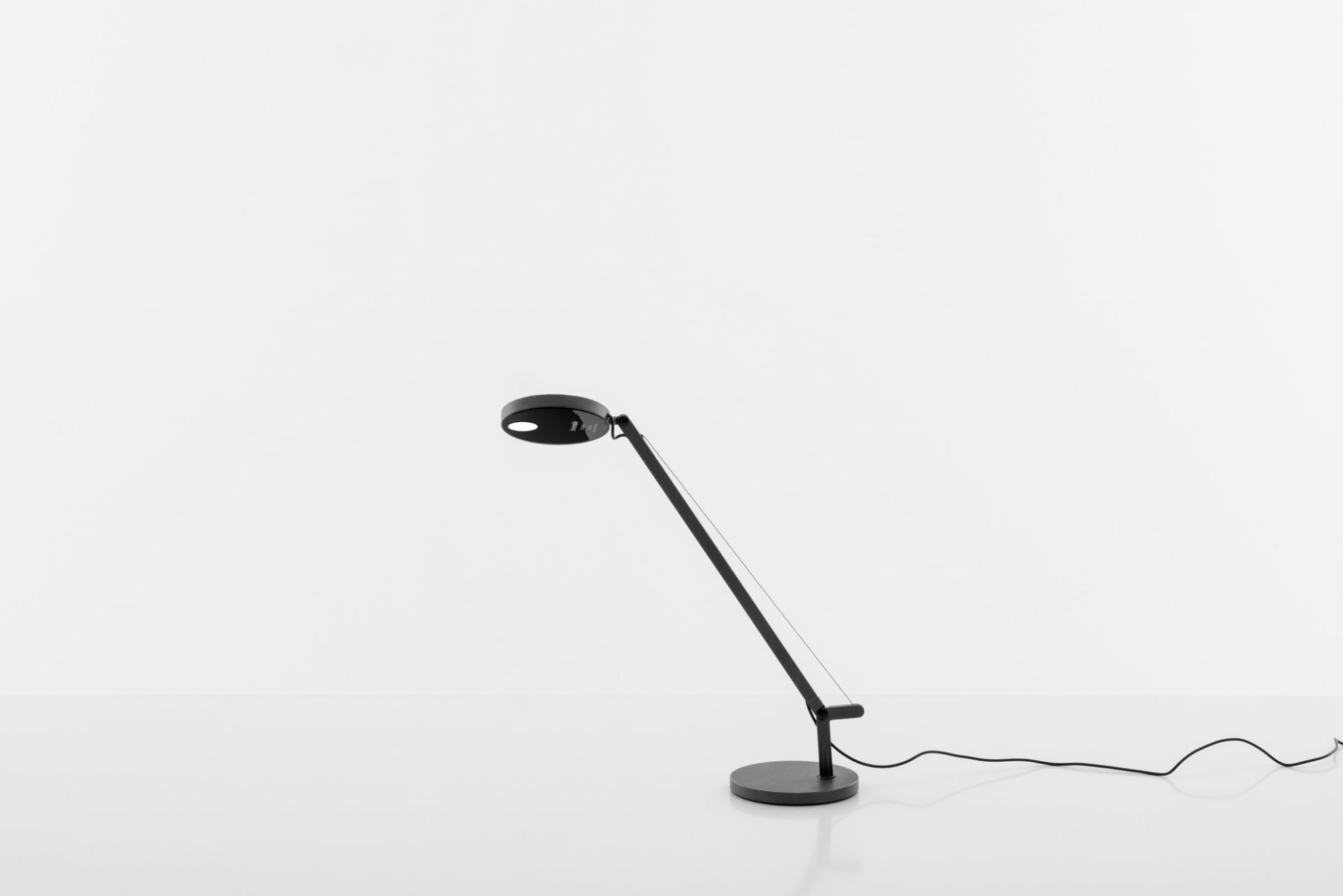 Schwarze Demetra Micro Tischleuchte von Artemide mit rundem Lampenkopf und verstellbarem Arm.