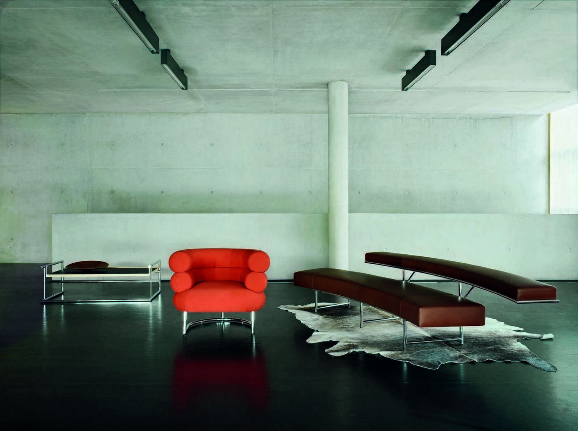 Menton Tisch von ClassiCon, orangefarbener Sessel und braune Bänke mit Chromgestell in modernem Raum.