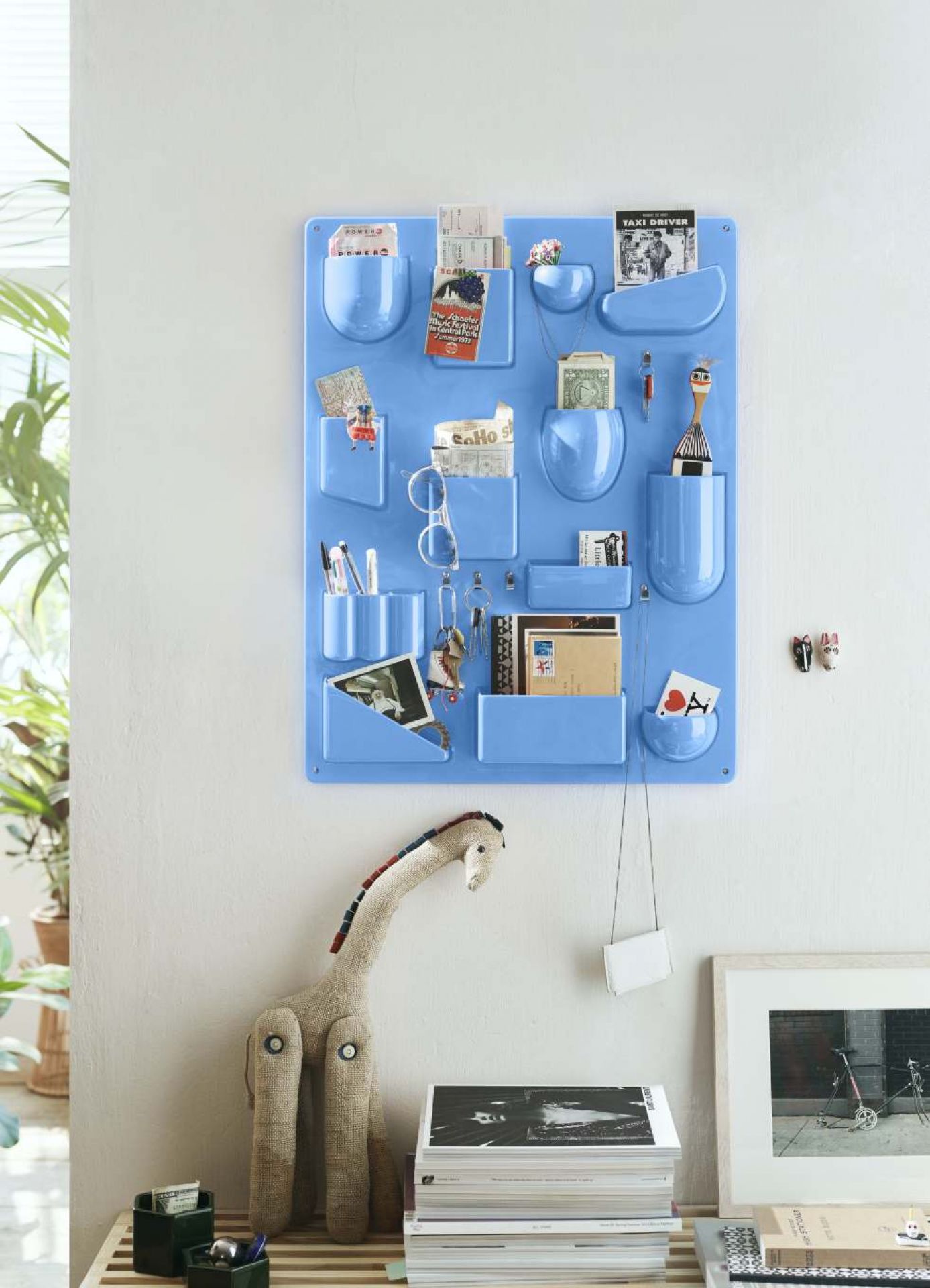 Blaues Uten.Silo Wand-Ordnungssystem von Vitra mit diversen Gegenständen in Taschen und Ablagen an einer weißen Wand.