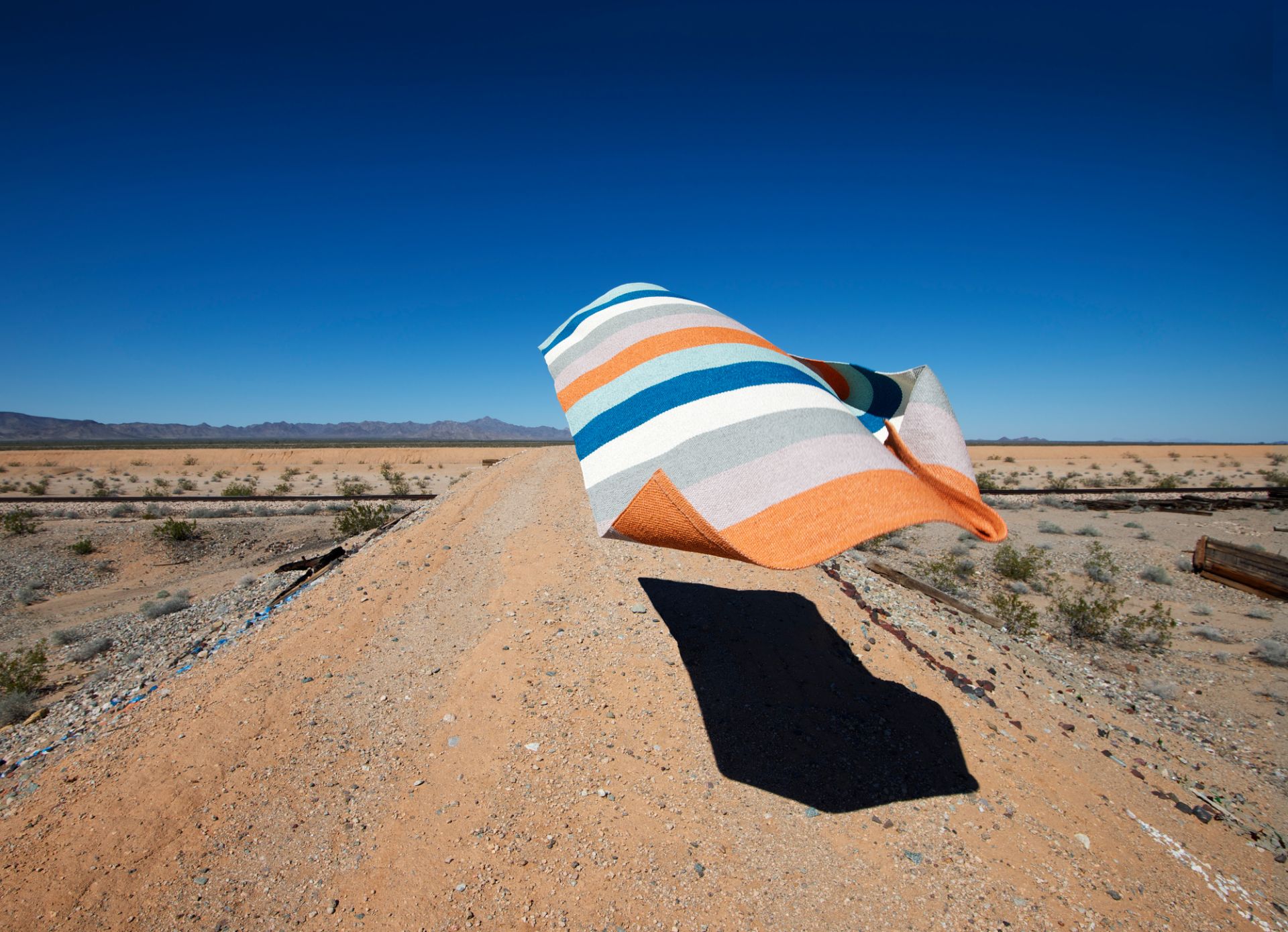 Muster des Molly Kunststoffteppichs von Pappelina, gestreift in Orange, Blau und Weiß.