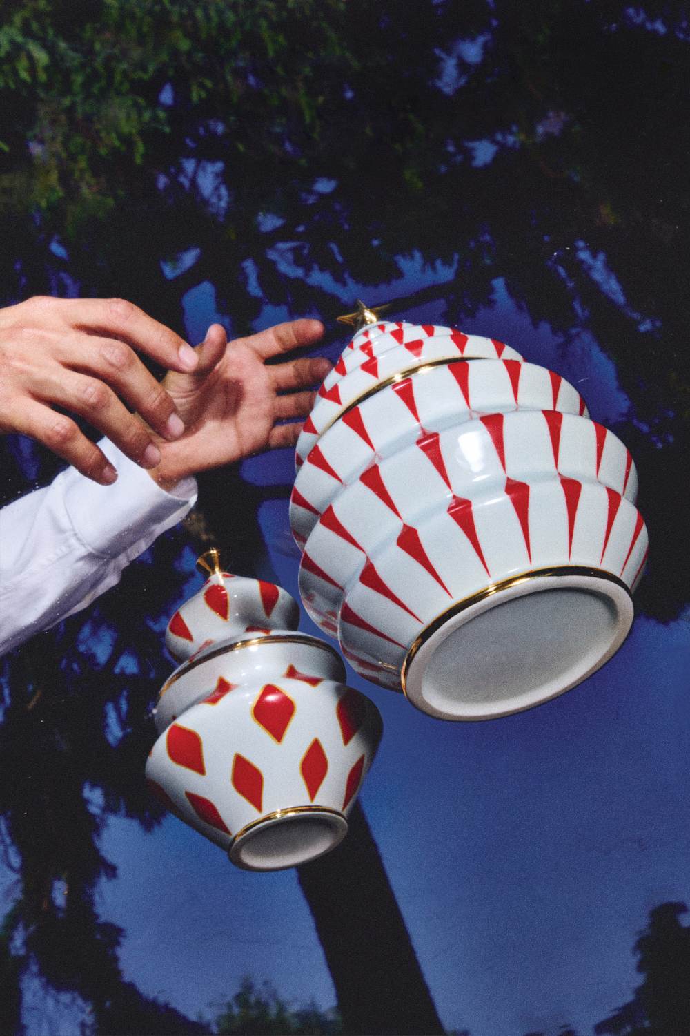 Alessi Keksdose NZ02 Delight: Zwei dekorative, weiße Keramikdosen mit roten Mustern und goldenen Akzenten.