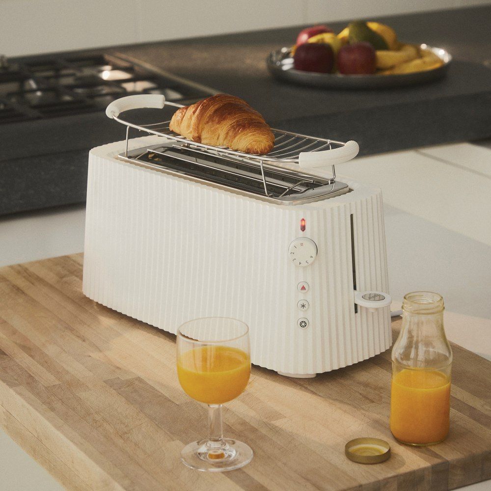 Weißer Alessi Plissé Toaster mit Croissant, Saft und Obst. Moderner Toaster für köstliches Frühstück.
