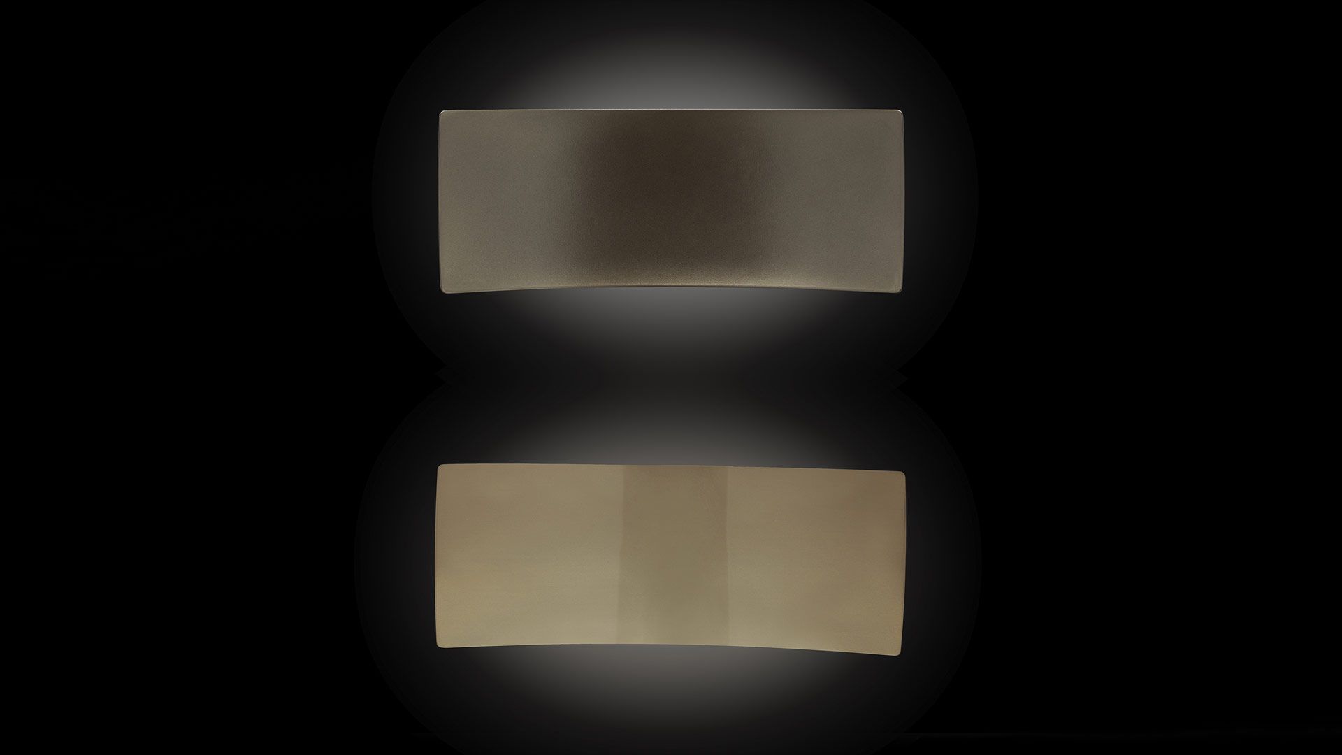 Oluce Lens Wandleuchte: Zwei rechteckige, goldfarbene Wandlampen mit indirektem Licht auf schwarzem Hintergrund.