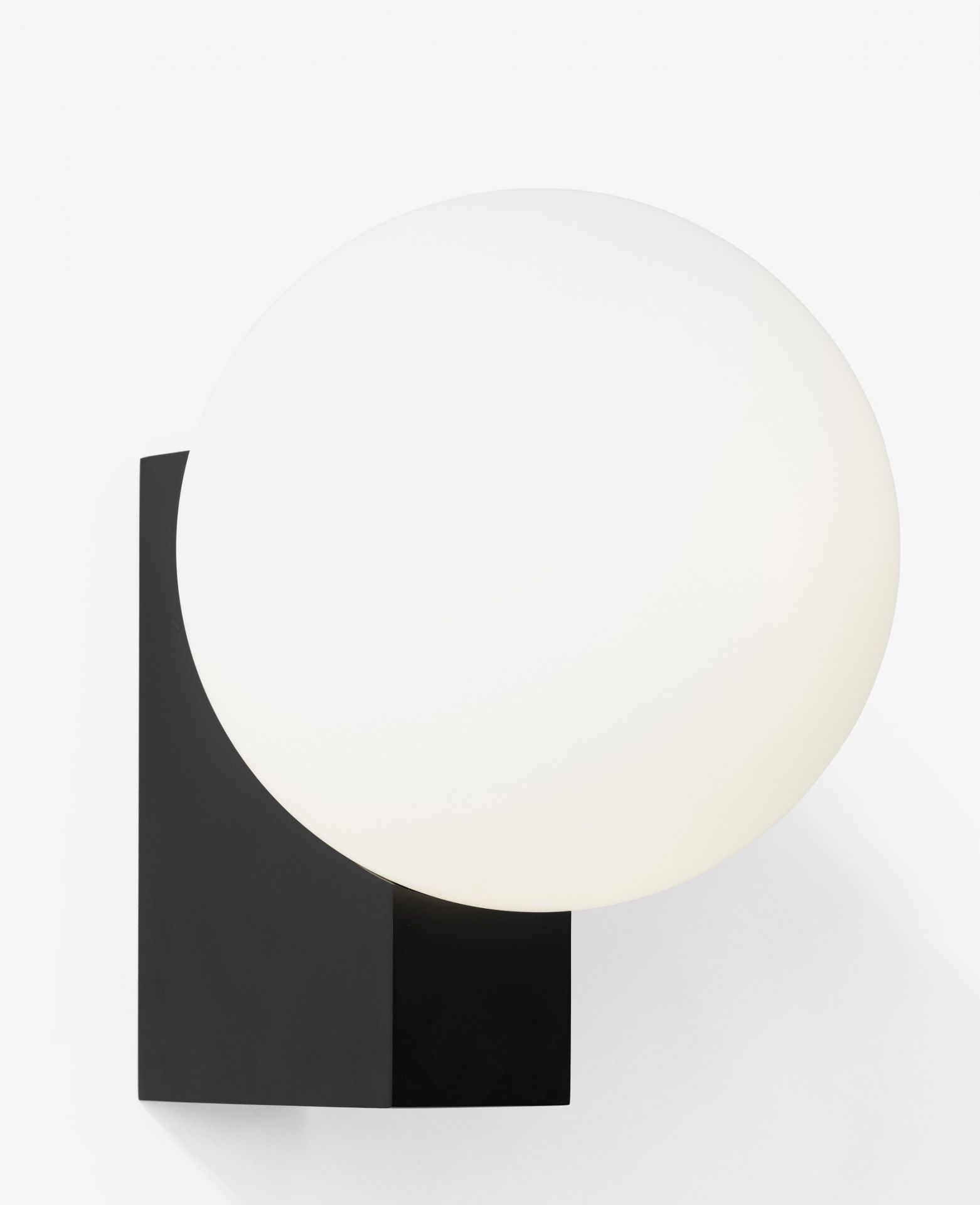 Nahaufnahme der Journey Wandleuchte von AndTradition mit schwarzem Sockel und weißem Glasschirm.