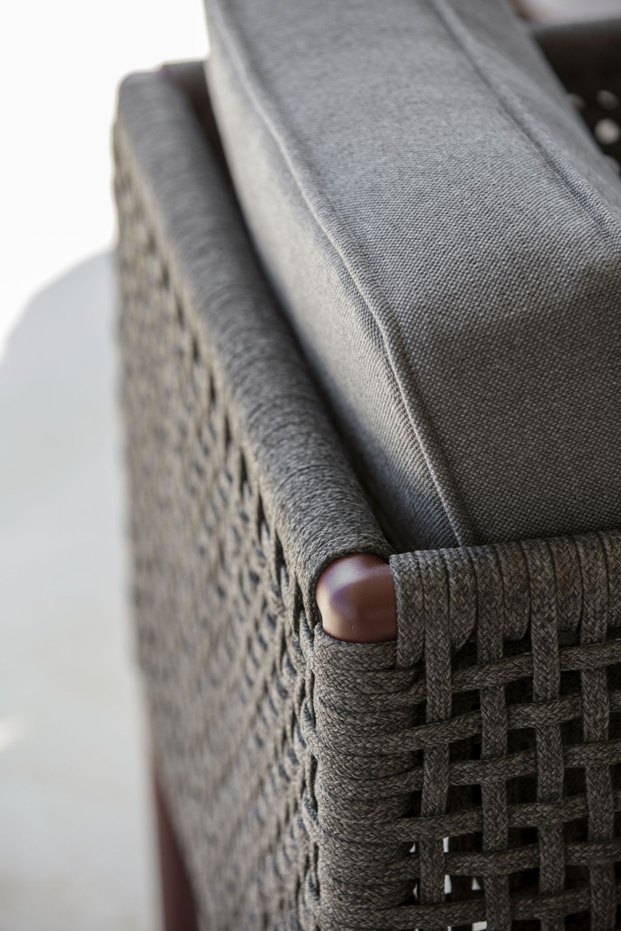 Detailaufnahme des Cane-Line Encore Loungesessels mit AirTouch Kissen, Cane-Line Geflecht und Holzarmlehne.