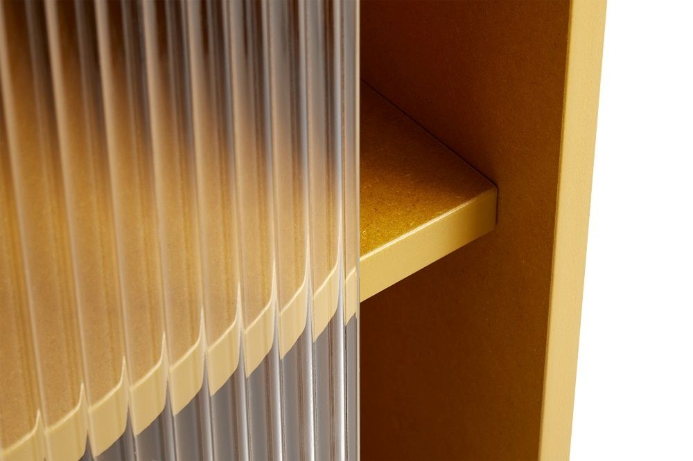 Detailaufnahme: Gelber Hay Schrank mit geriffelter Glastür und Innenregal. Moderner Stauraum.