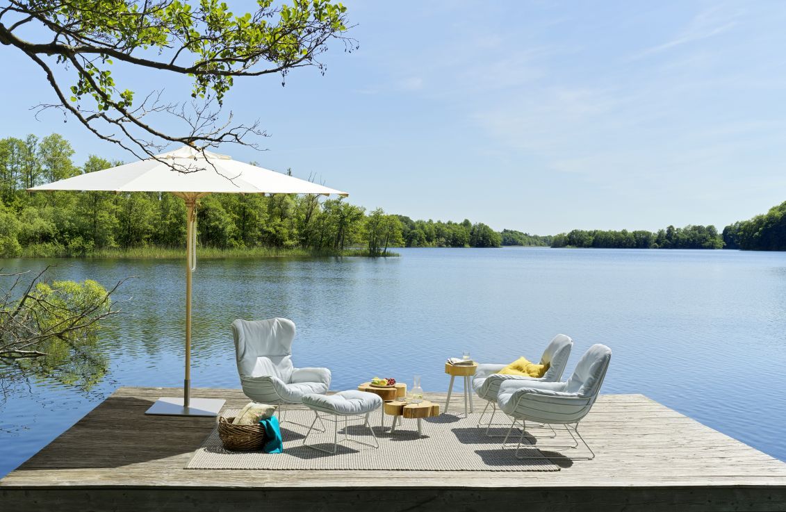 Leyasol Ottoman Outdoor: Elegante Gartenmöbel auf Holzsteg am See mit Sonnenschirm. Freifrau Manufaktur Design.
