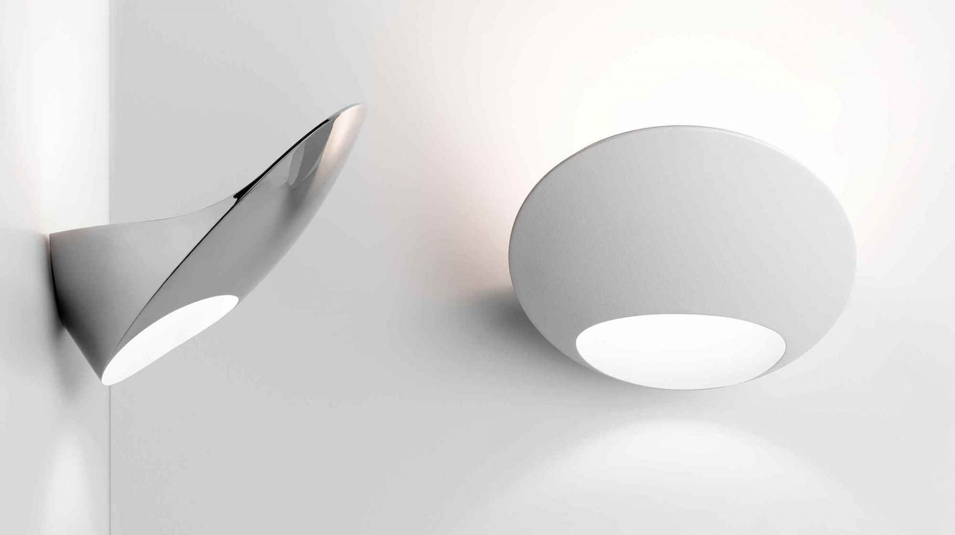 Zwei moderne Wandleuchten, darunter die D90 Garbi, in Weiß und Silber an einer weißen Wand.