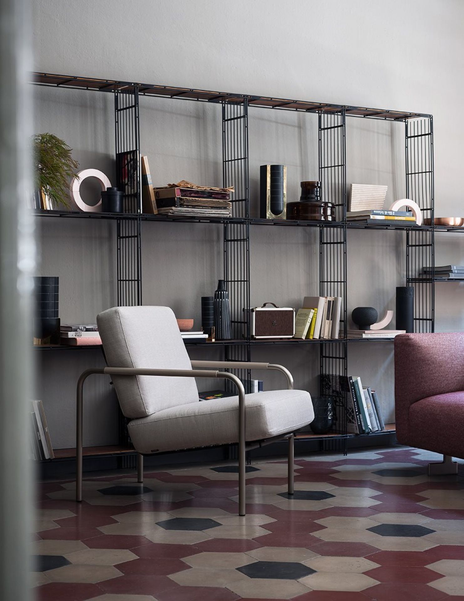 Eleganter Susanna Sessel von Zanotta in hellem Stoff vor einem schwarzen Bücherregal. Designermöbel für stilvolles Wohnen.