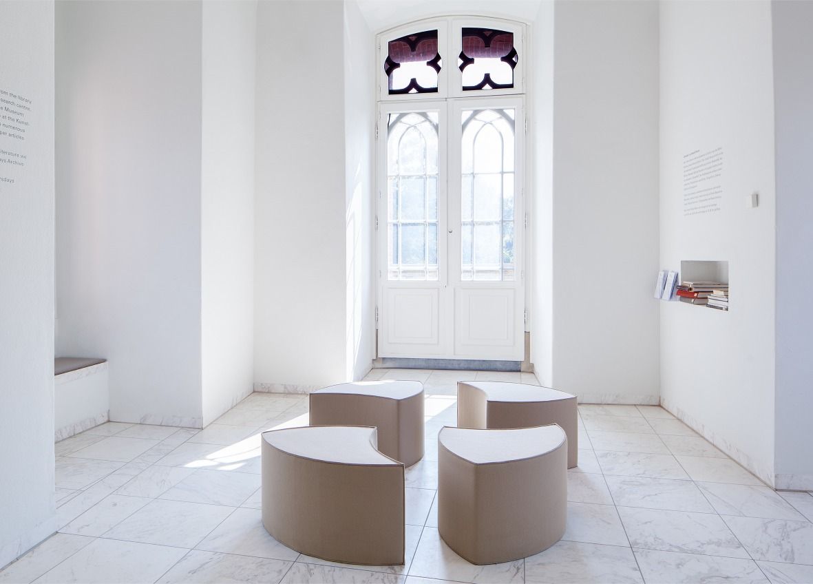 Posito Sitzmöbel von Hey Sign: Vier graue, halbkreisförmige Filzhocker in einem hellen Raum. Sitzmöbel für Wohnen und Büro.