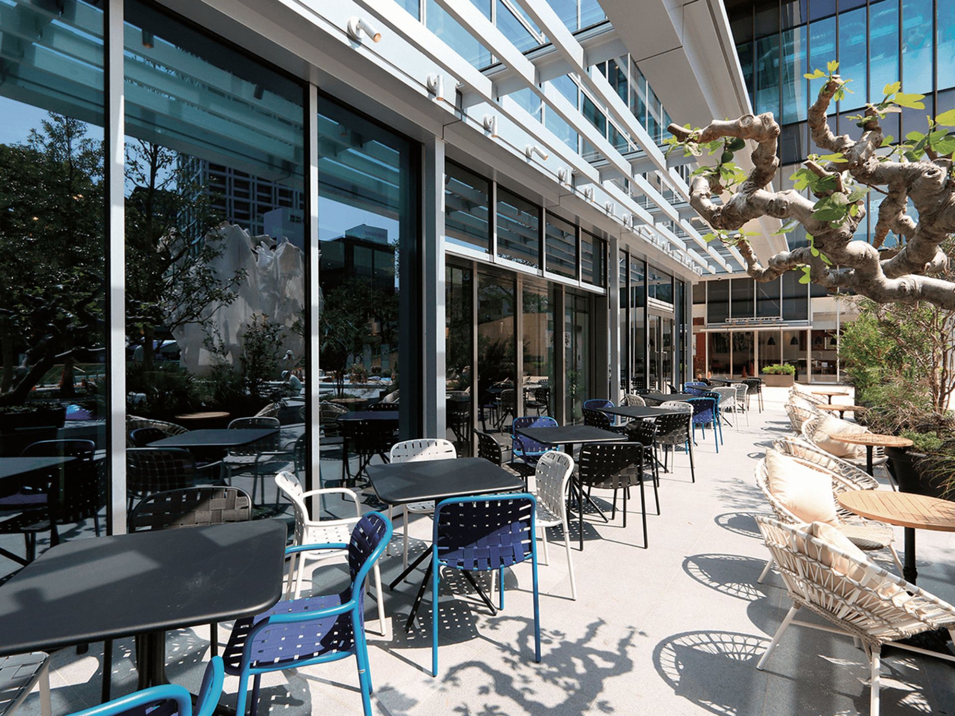 Außenbereich mit Emu Yard Stühlen in verschiedenen Farben und Tischen auf einer Terrasse.