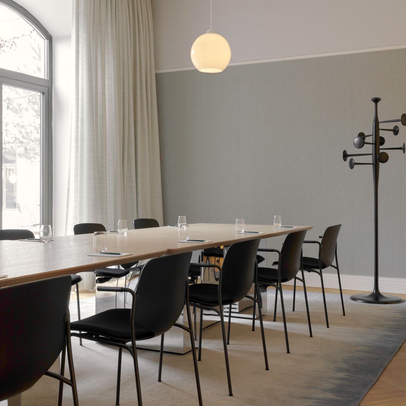 Konferenzraum mit langem Tisch und schwarzen Nova Sea Stühlen von Mater, gepolsterte Sitzfläche.