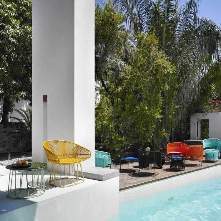 Gelber Circo Dining Chair Outdoor von ames auf Terrasse mit Pool und Garten.