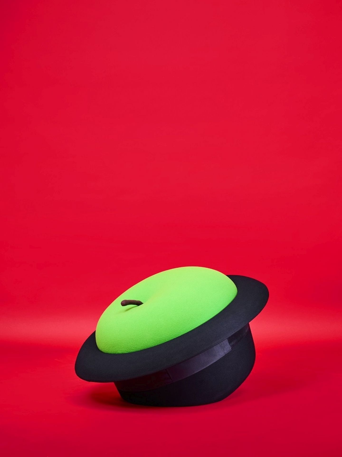 MagriTTA Sessel-Pouf von Gufram: Skulpturaler Sitzhocker in Form eines grünen Apfels auf einem schwarzen Hut.