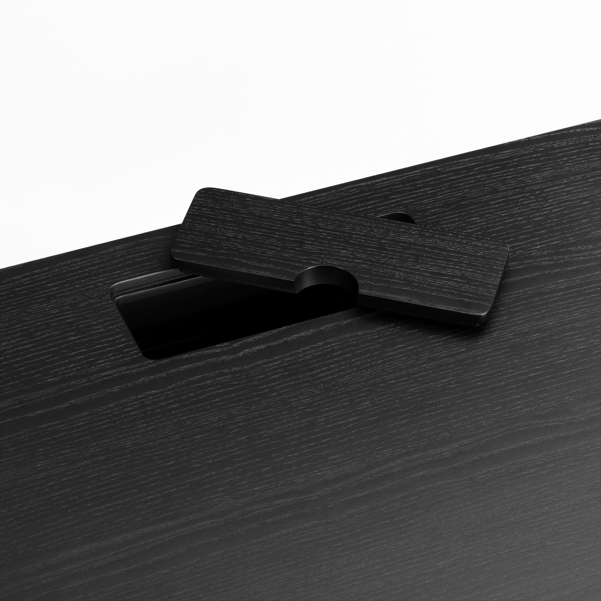 Detailaufnahme: Schwarzer JFK Schreibtisch von Norr11 mit Kabeldurchlass für modernes Bürodesign.