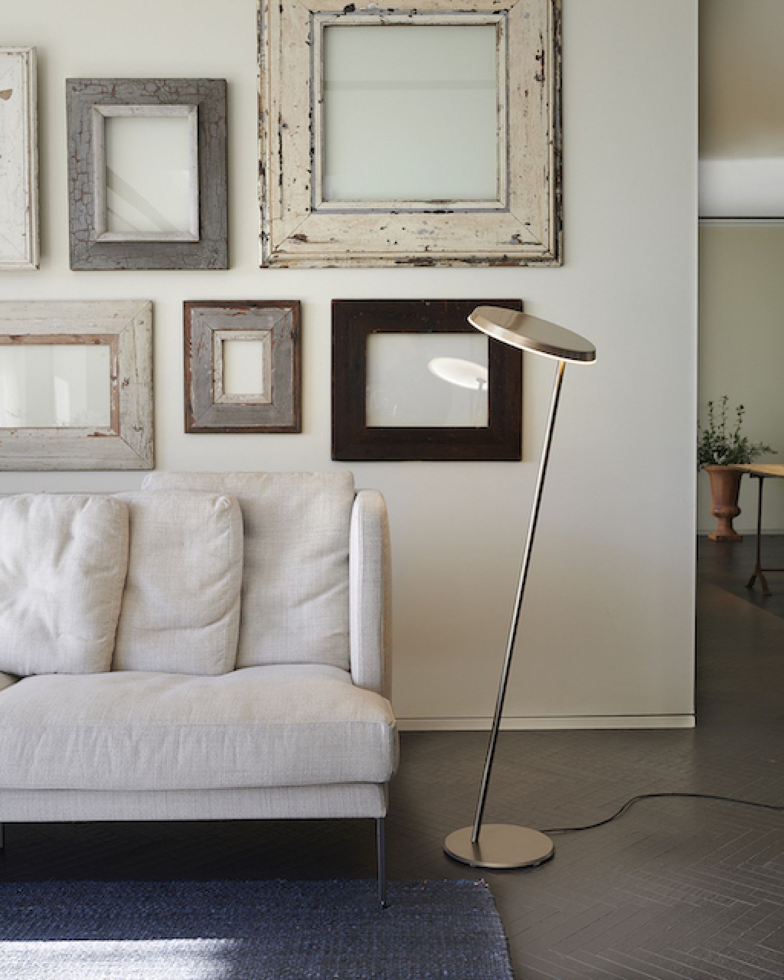 Amanita LED Stehleuchte von Oluce neben Sofa und Bilderrahmen im Wohnzimmer.
