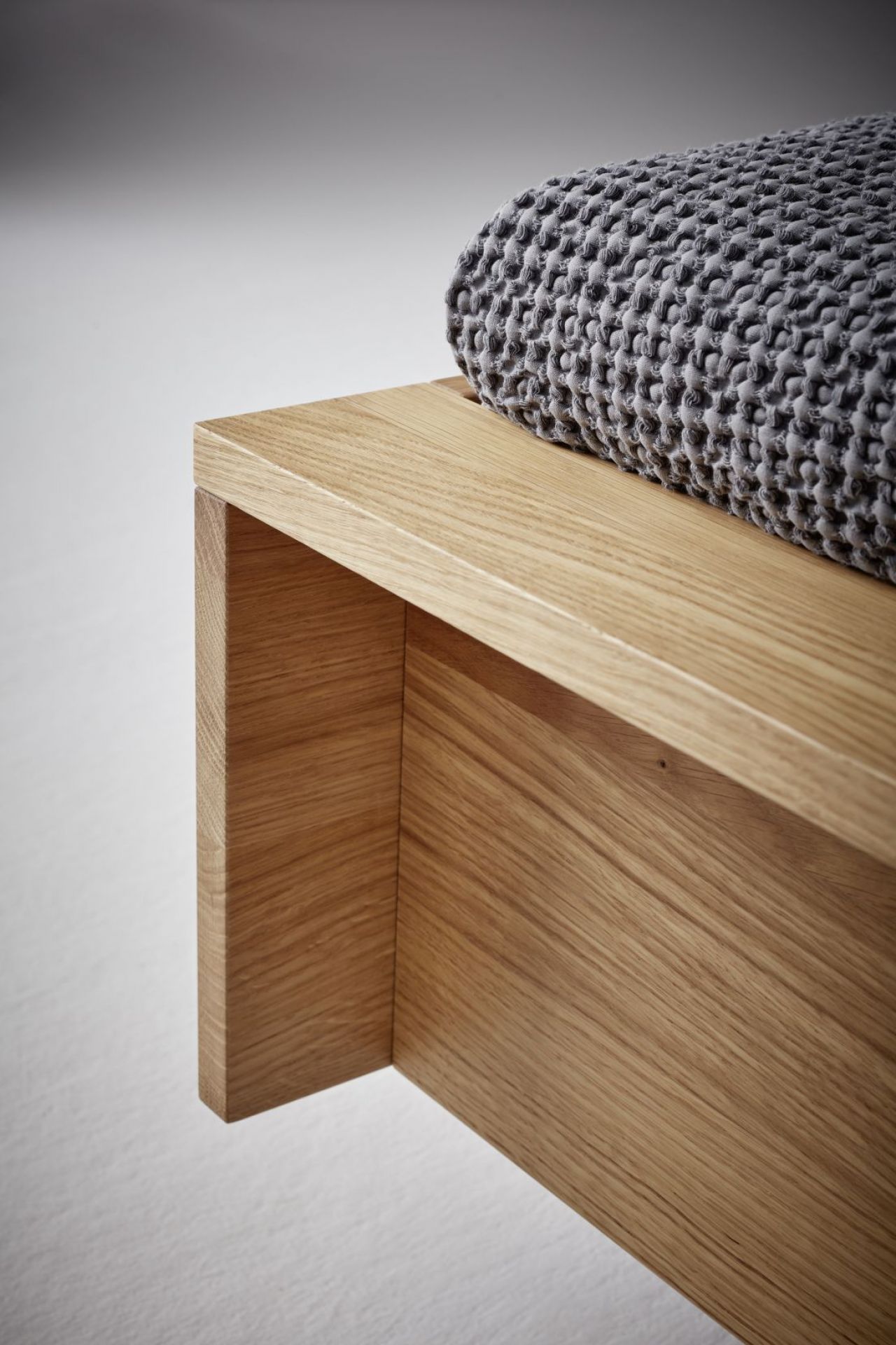 Detailaufnahme vom Flai Bett Eiche von Müller Möbelwerkstätten mit grauer Tagesdecke.