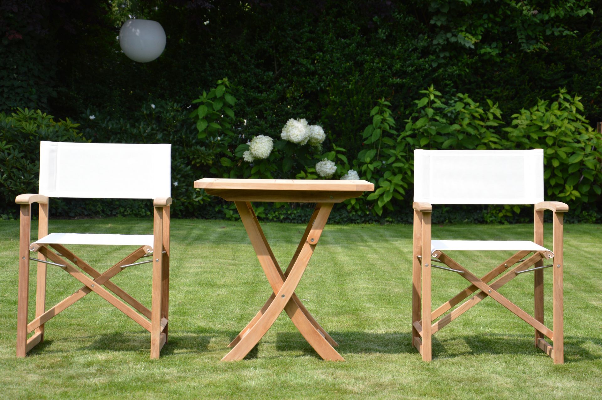 Urban Regiestuhl von Jan Kurtz mit taupefarbenem Bezug und passendem Beistelltisch aus Holz im Garten.