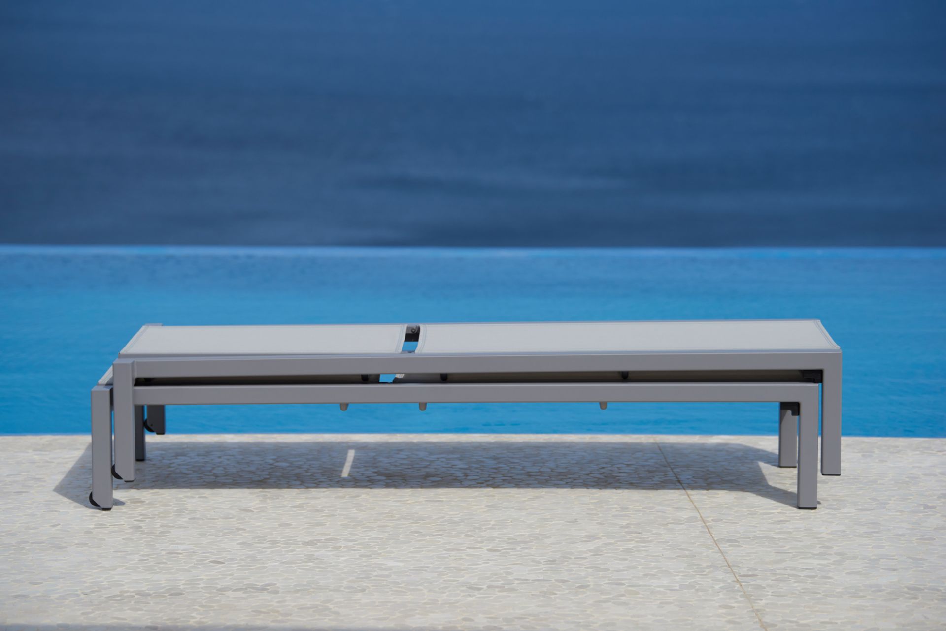 Nahaufnahme einer Cane-Line Sonnenliege ohne Kissen, hellgraues Gestell, für den Outdoor-Bereich.