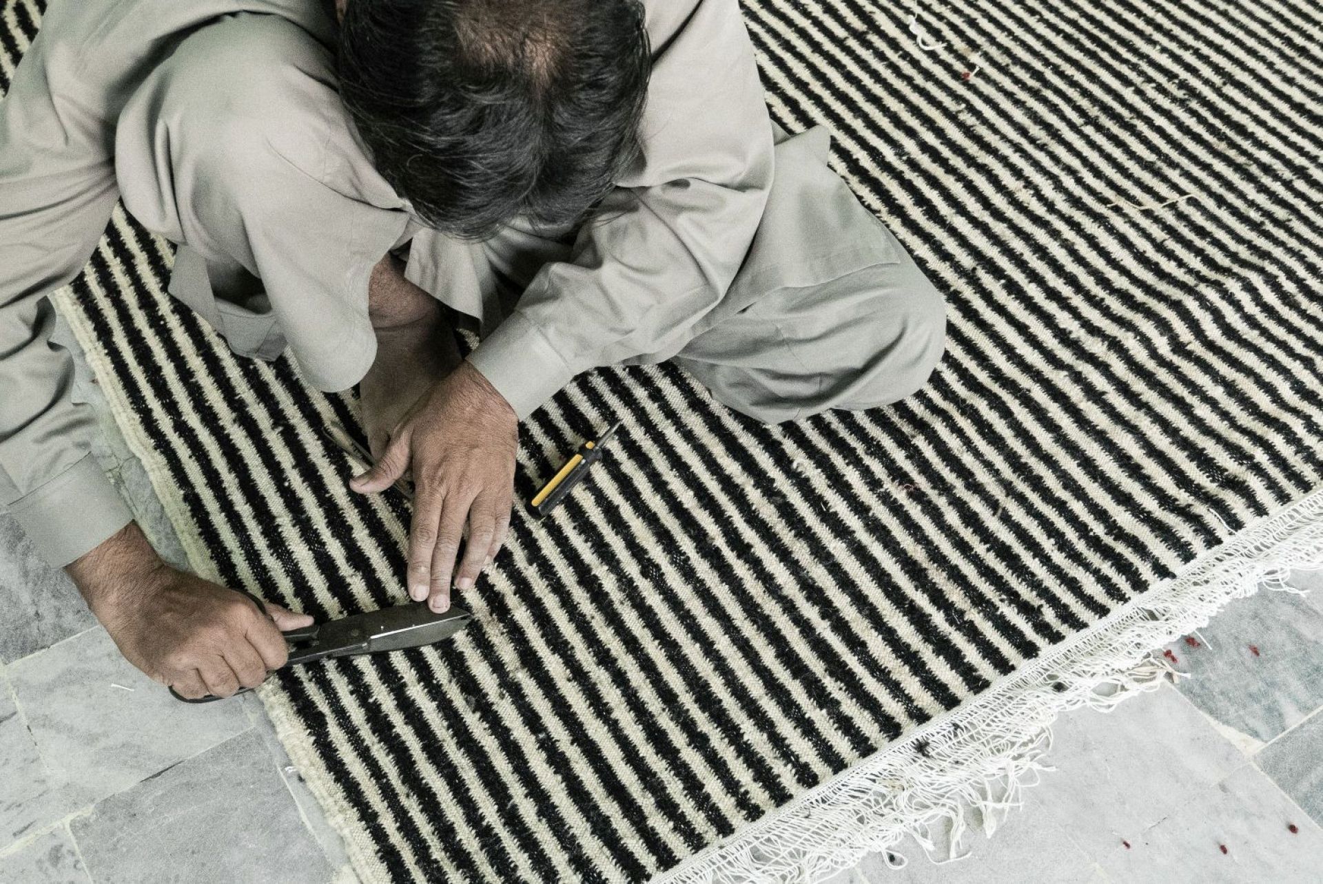 Handwerker bearbeitet Nanimarquina Läufer mit Streifenmuster. Hochwertiger Teppich für stilvolles Wohnen.