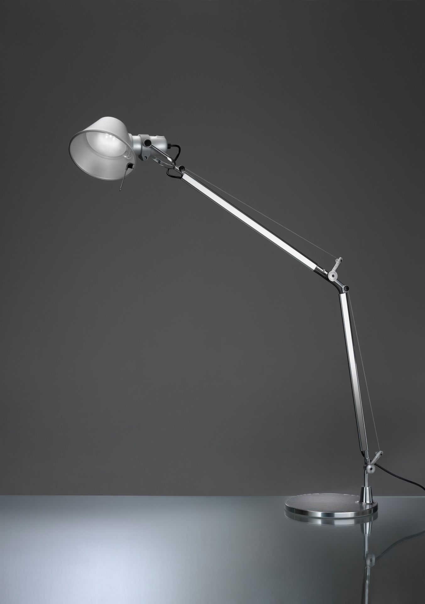 Silberne Tolomeo Tischleuchte von Artemide mit verstellbarem Arm und Lampenschirm auf einem grauen Hintergrund.