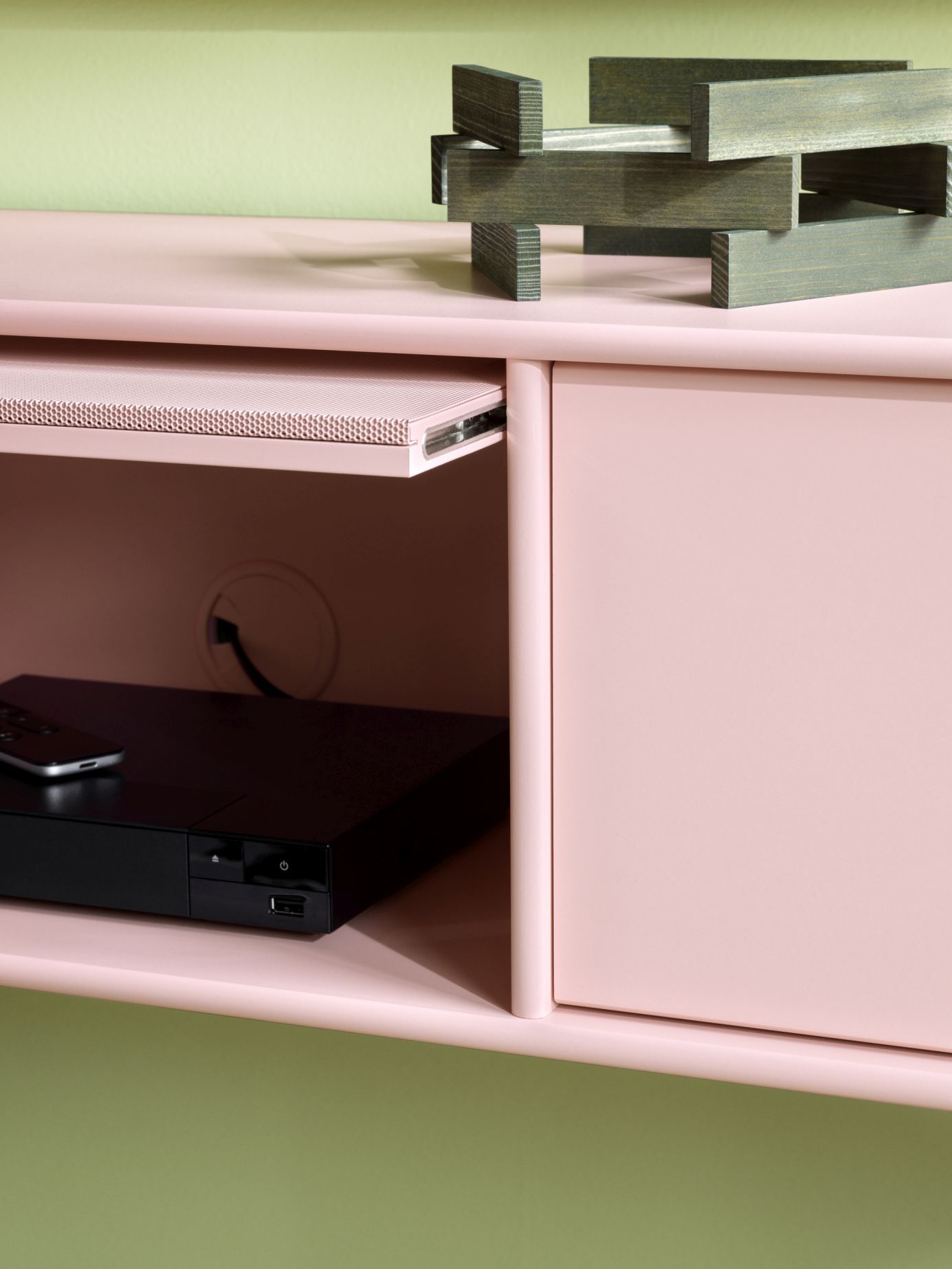 Octave V TV-Bank in Fennel: Detailansicht mit schwarzem Gestell, offenem Fach und Mediengerät.