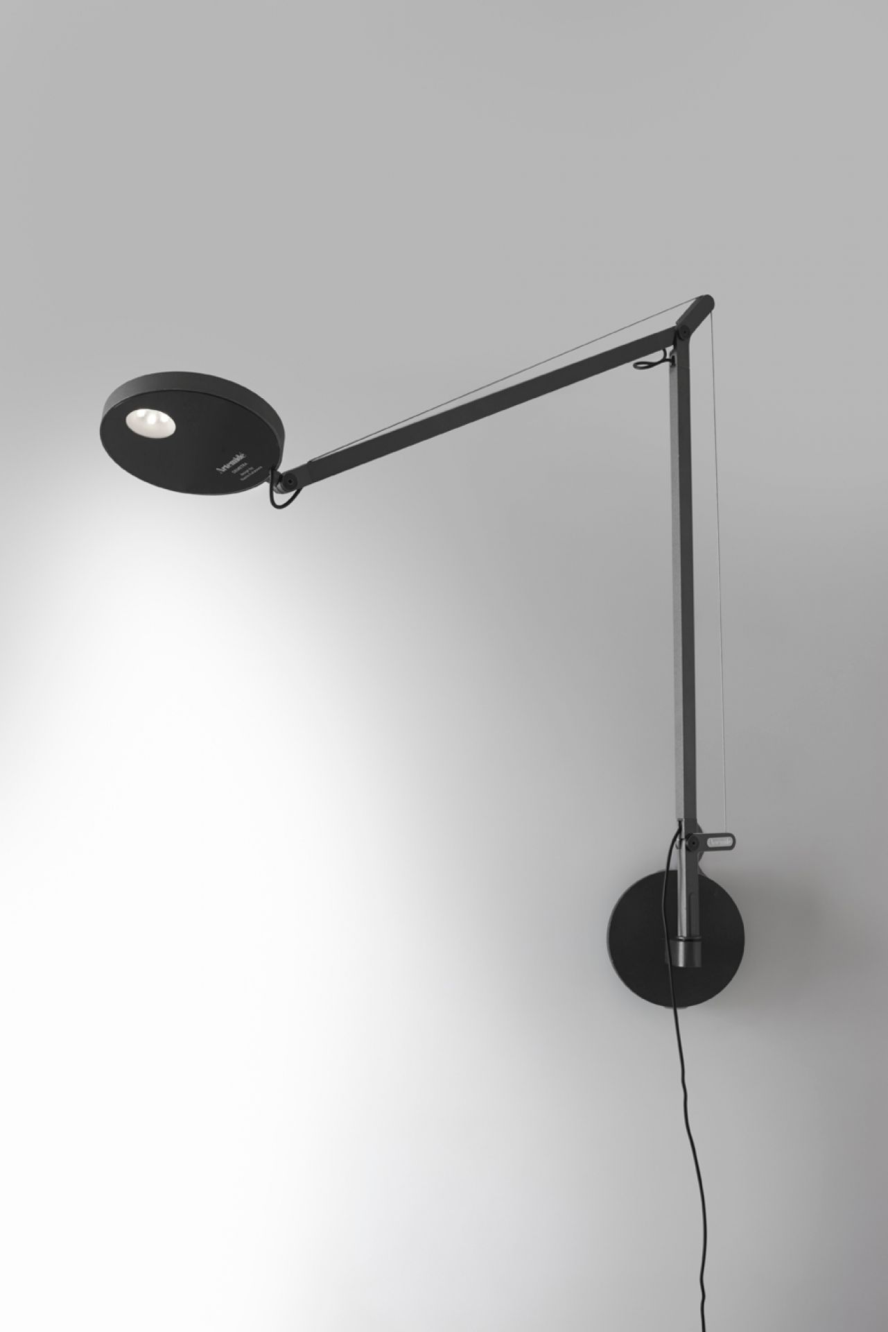 Schwarze Demetra Wandleuchte von Artemide mit verstellbarem Arm und runder Wandhalterung.