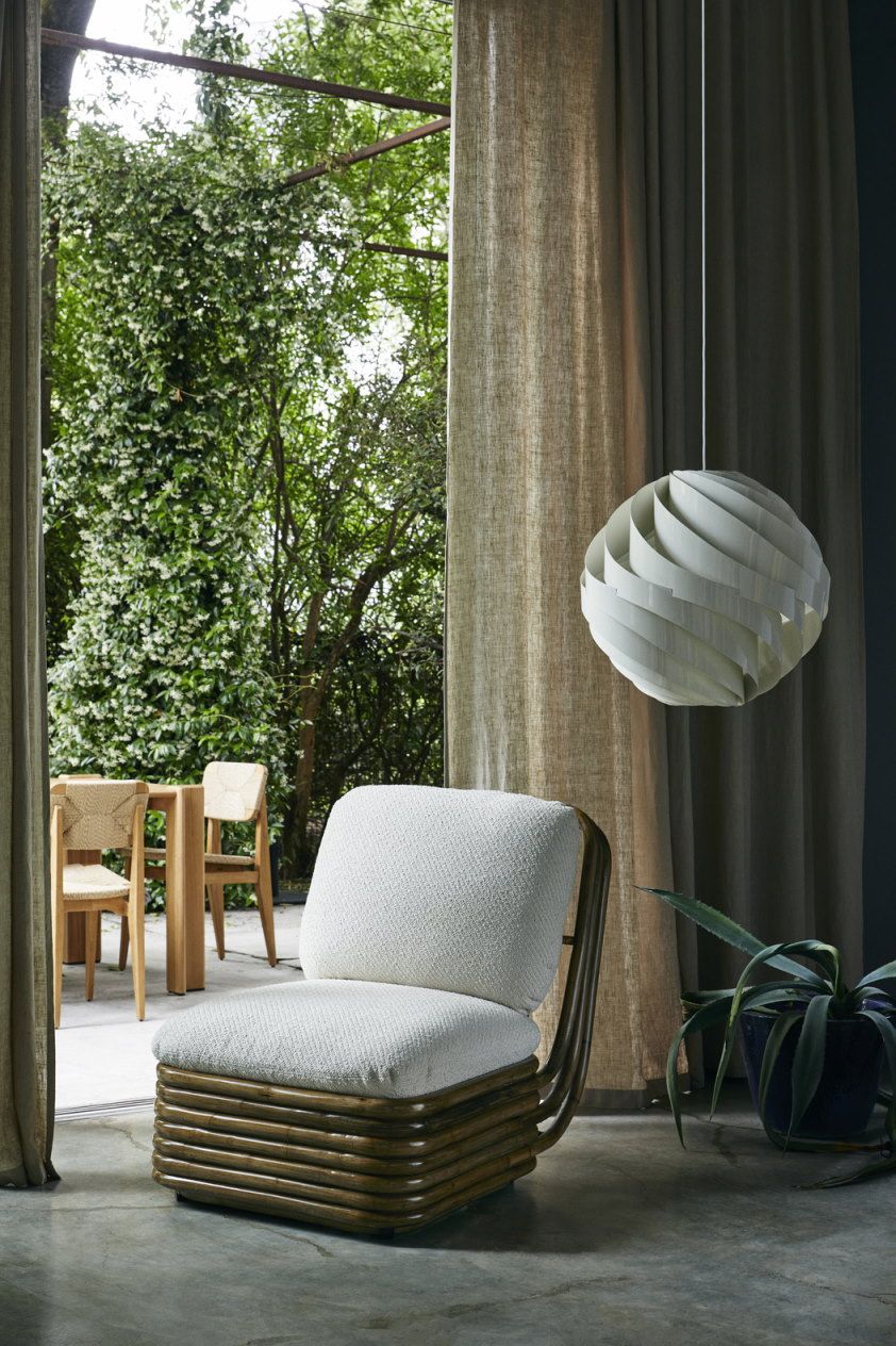 Weiße Turbo Pendelleuchte von Gubi, spiralförmiges Design, hängend über Sessel in heller, moderner Inneneinrichtung.