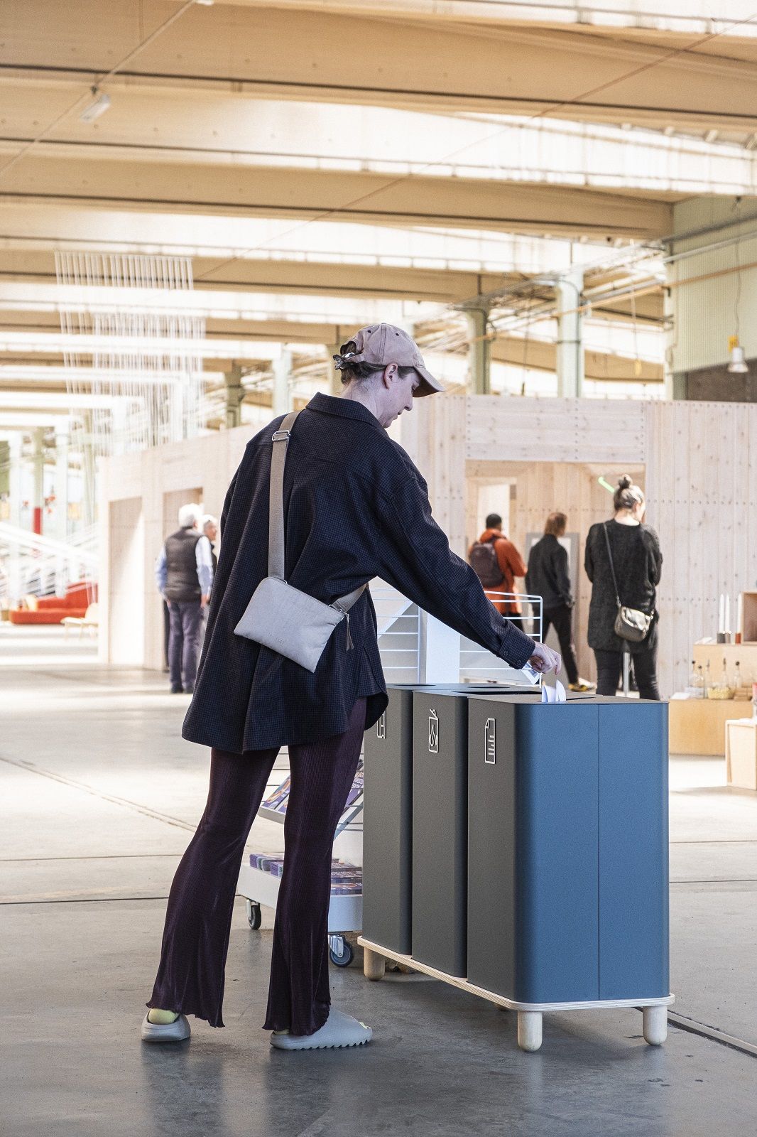 Person wirft Papier in Arkad Bin Mülleimer zur Mülltrennung von Mizetto. Nachhaltige Abfallbehälter für Büro.