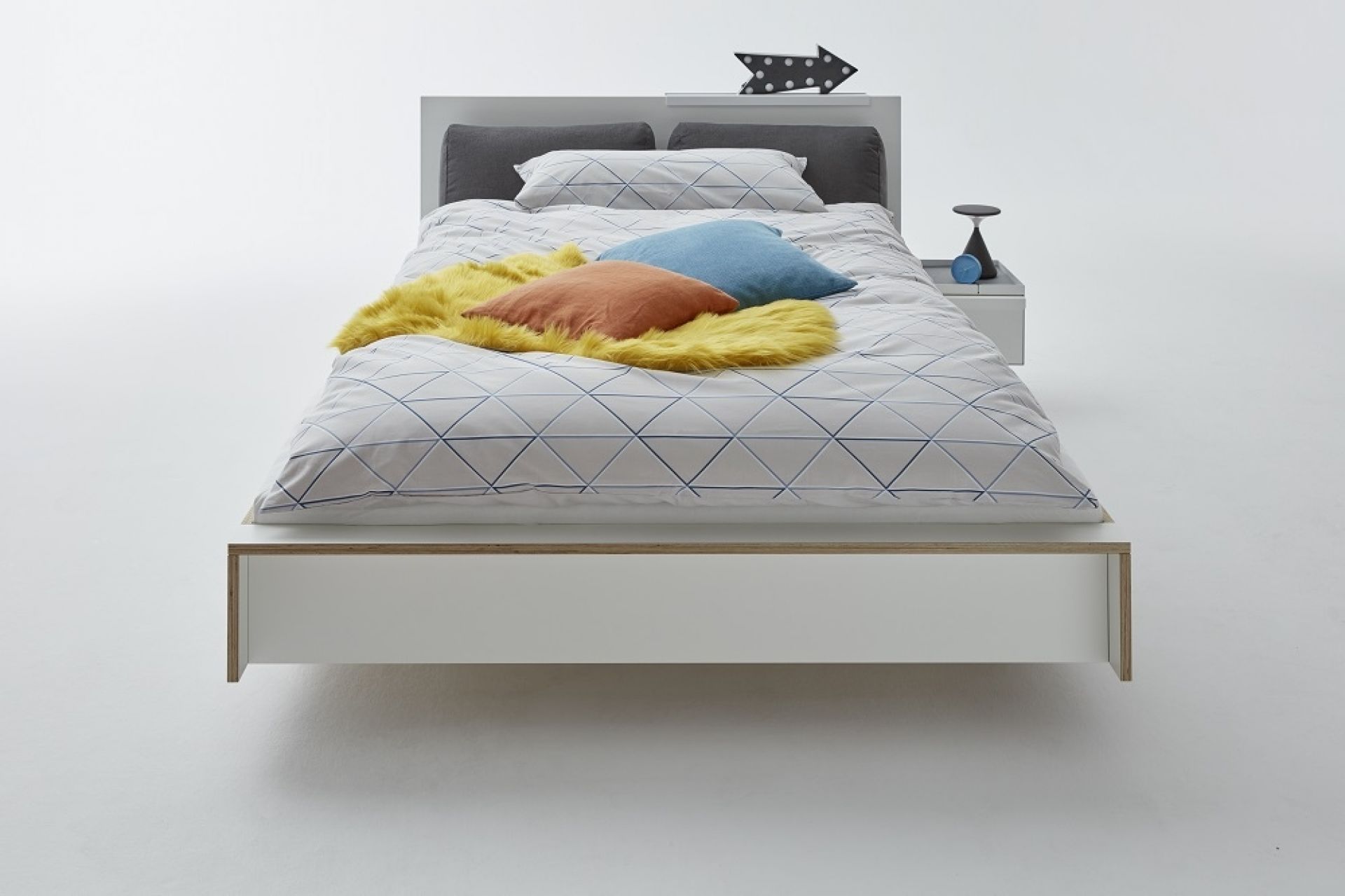 Weißes Flai Einzelbett von Müller Möbelwerkstätten mit Bettwäsche und Nachttisch.
