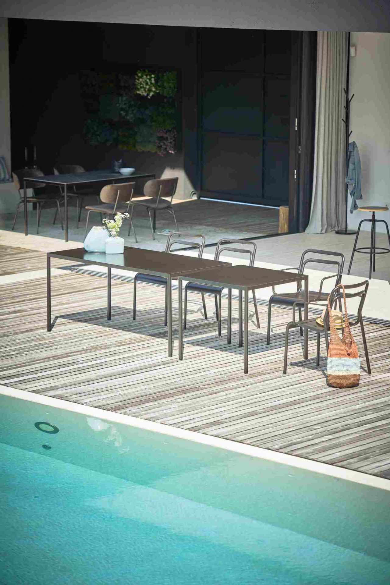 Schwarzer Jan Kurtz Outdoor Tisch "Live" neben Pool auf Holzterrasse mit Stühlen. Gartentisch für Terrasse.