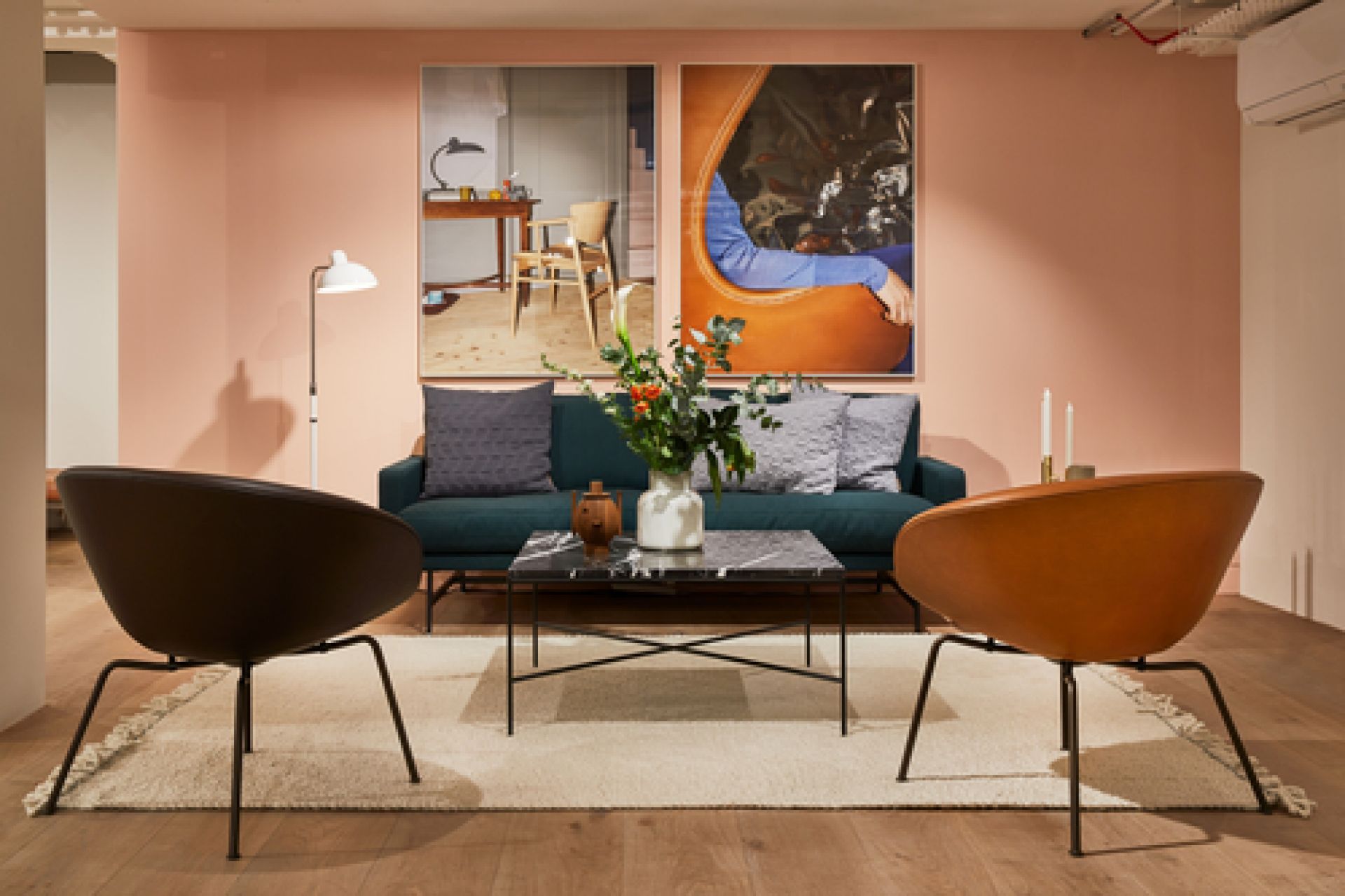 Wohnzimmer-Szene mit Fritz Hansen Couchtisch Planner, Sofa, Sesseln und Dekoration auf einem Teppich.