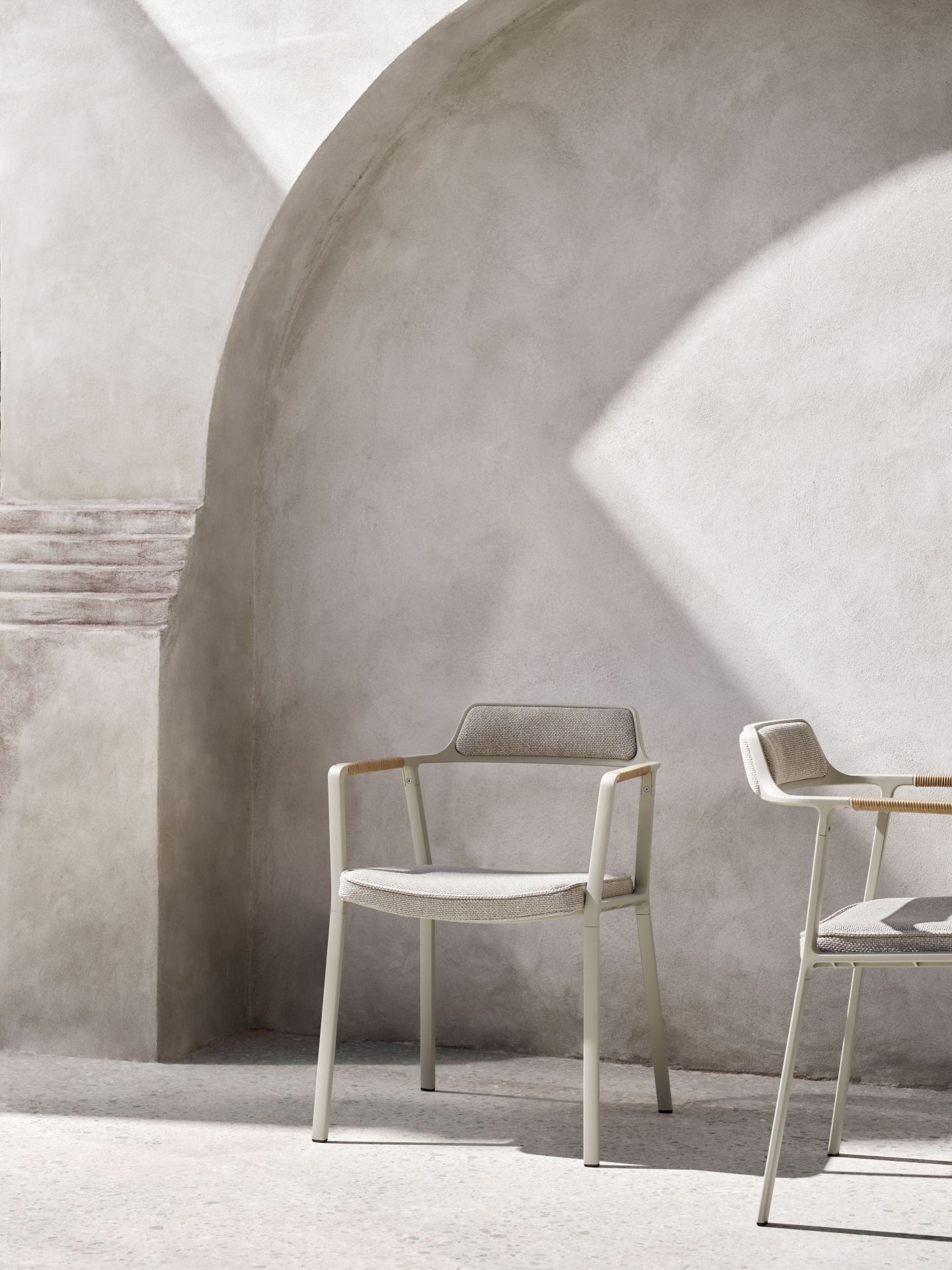 Zwei Vipp Open-Air Outdoor Stühle in Beige vor einer hellen Betonwand mit Treppe.