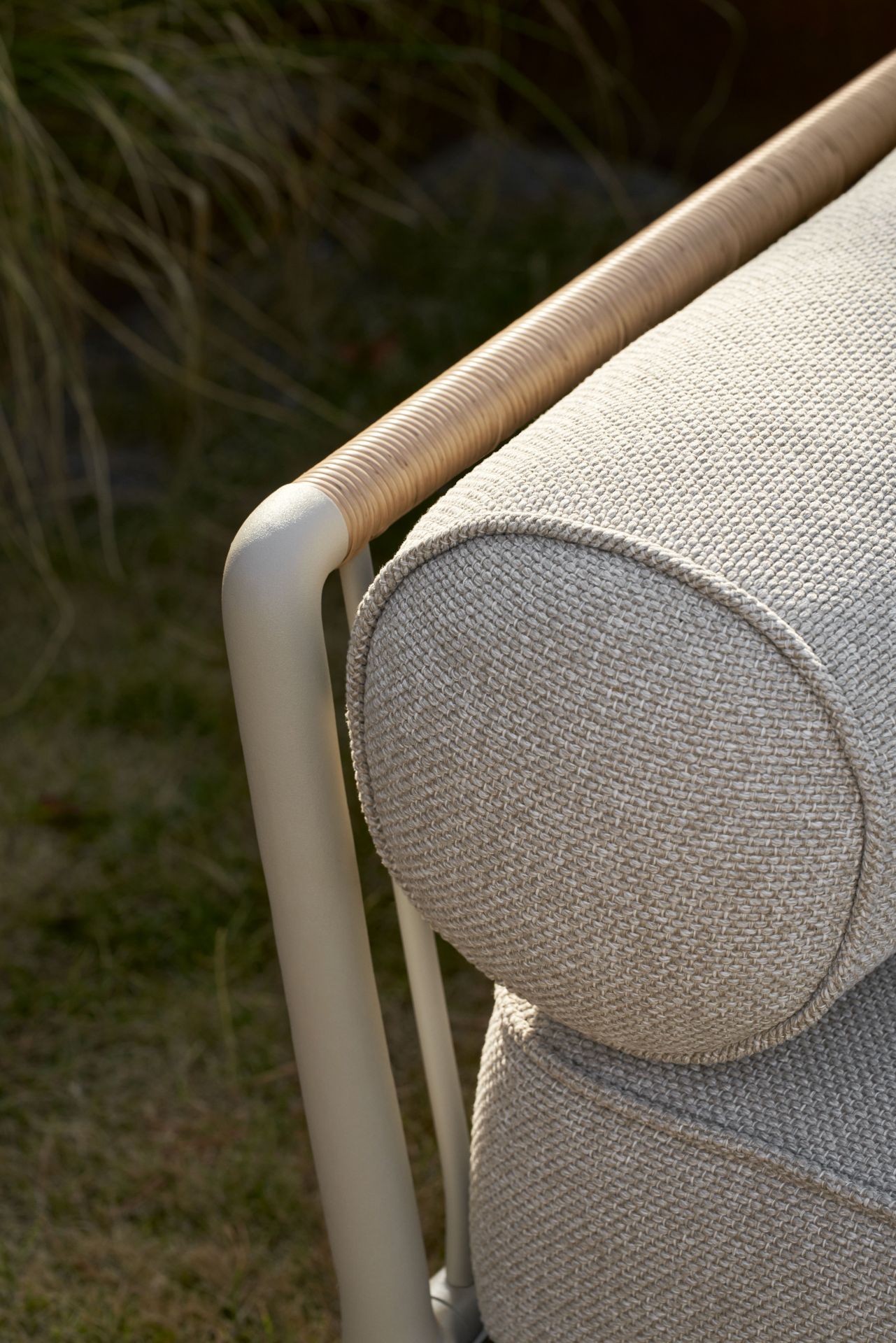 Detailaufnahme des Vipp Outdoor Sofas: Beige Polsterung und geflochtener Armlehne. Hochwertige Gartenmöbel für den Außenbereich.