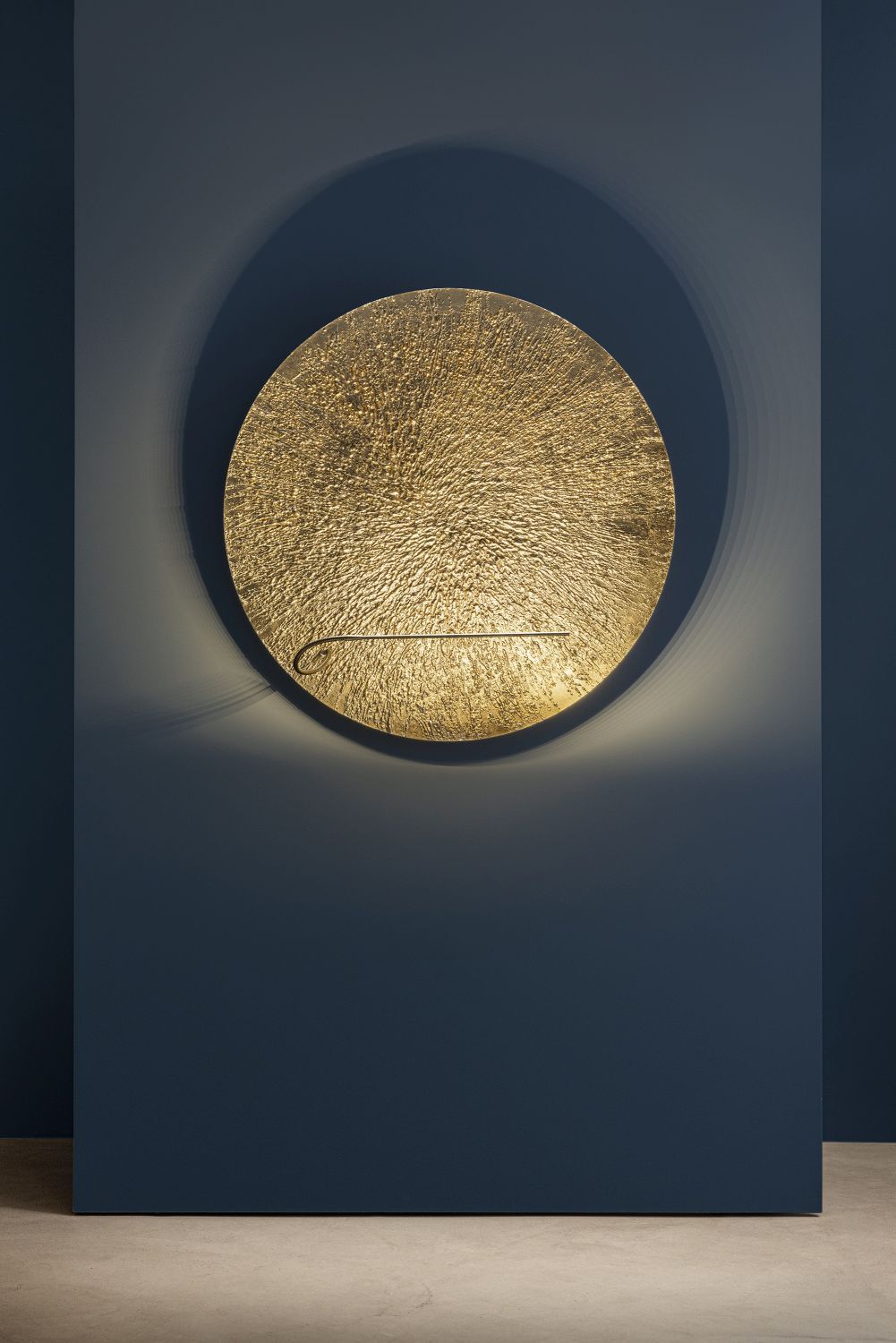 Goldene Bellatrix Wandleuchte von Catellani & Smith an blauer Wand, modernes Design, indirekte Beleuchtung.