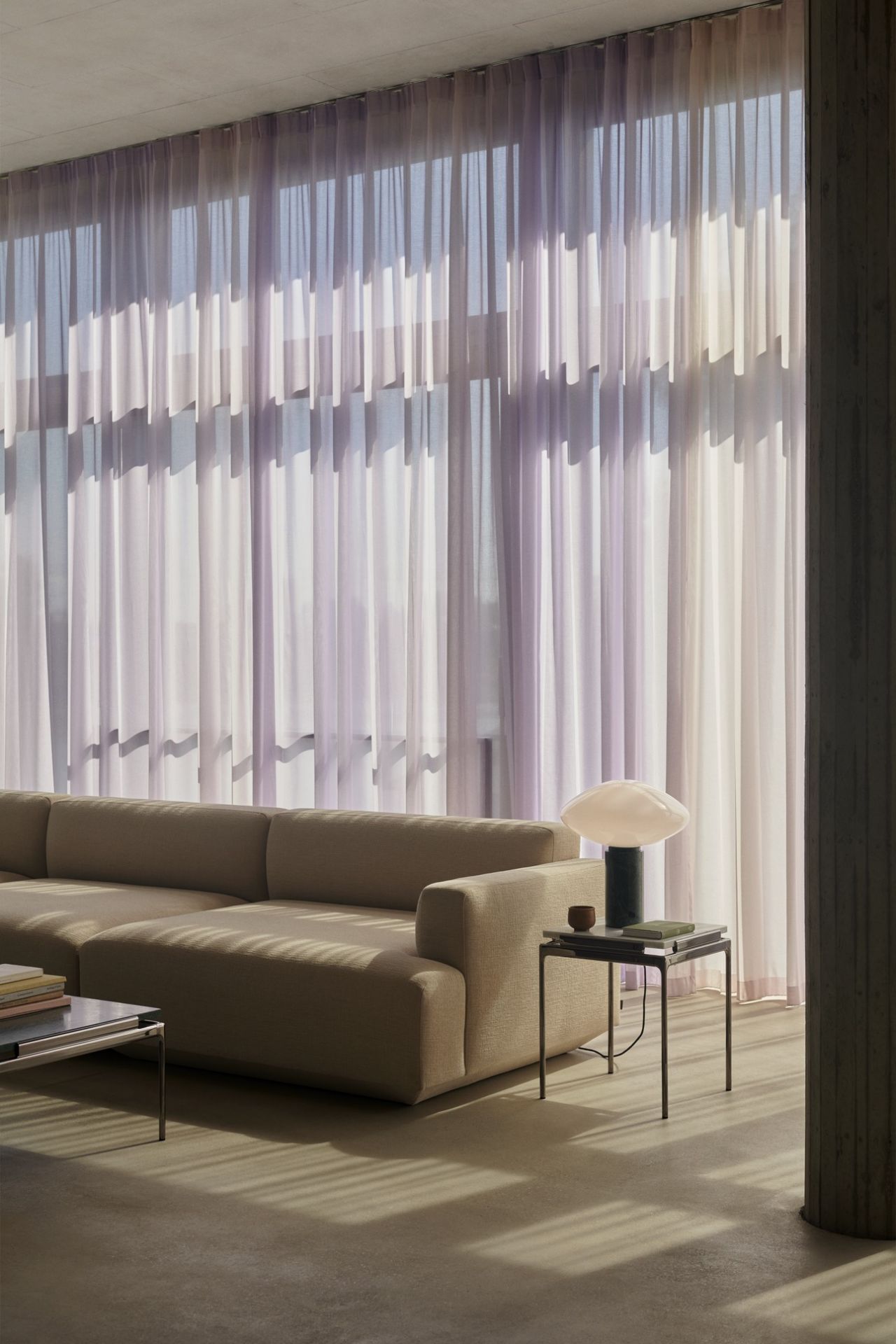 AndTradition Sett LN11 Beistelltisch neben Sofa mit Lampe und Büchern im Wohnzimmer.