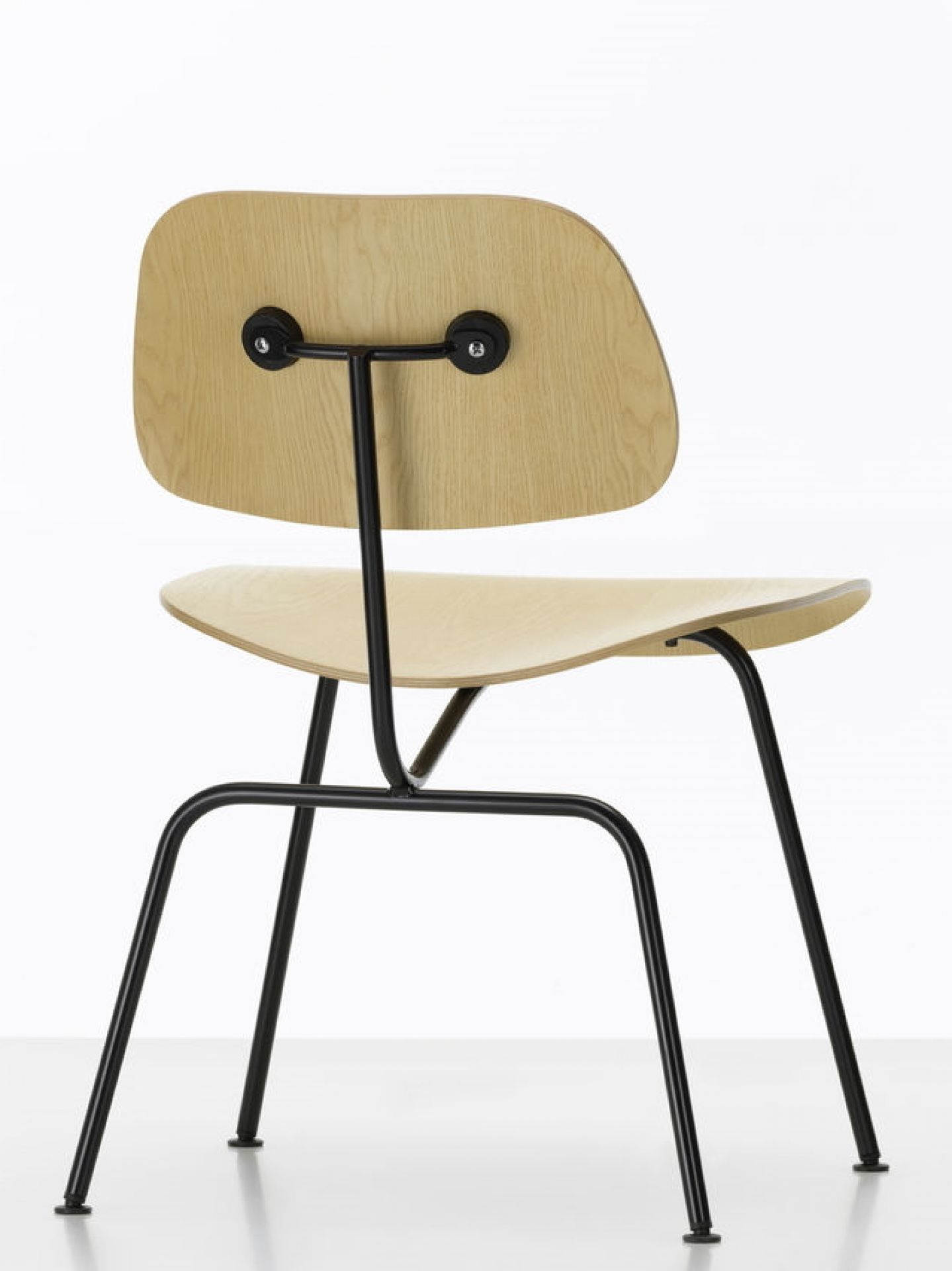 Rückansicht des Vitra Plywood Group Stuhls DCM mit hellem Holz und schwarzem Stahlgestell.