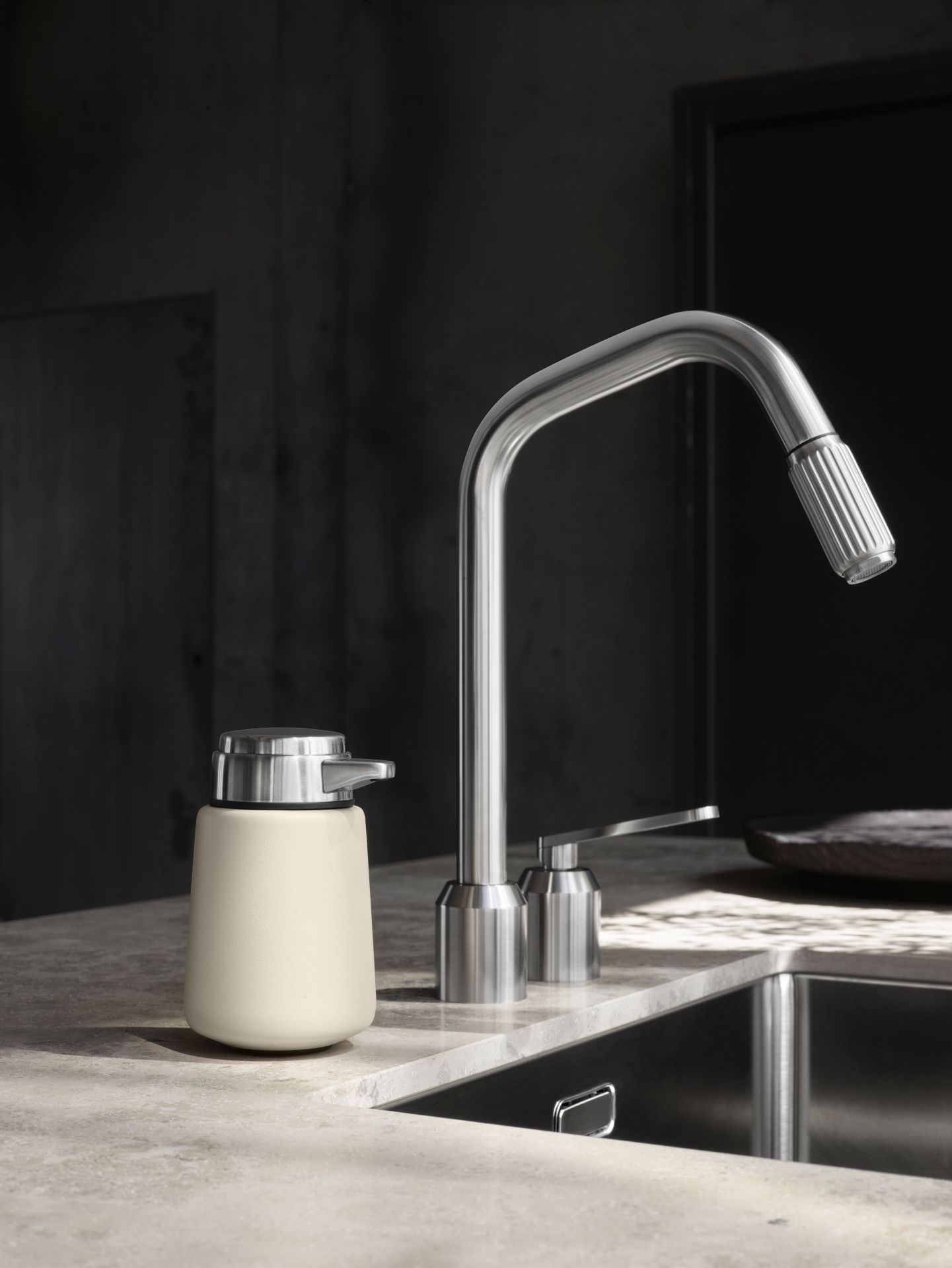 Beiger Vipp Seifenspender aus Edelstahl in moderner Küche neben Spüle und Armatur.