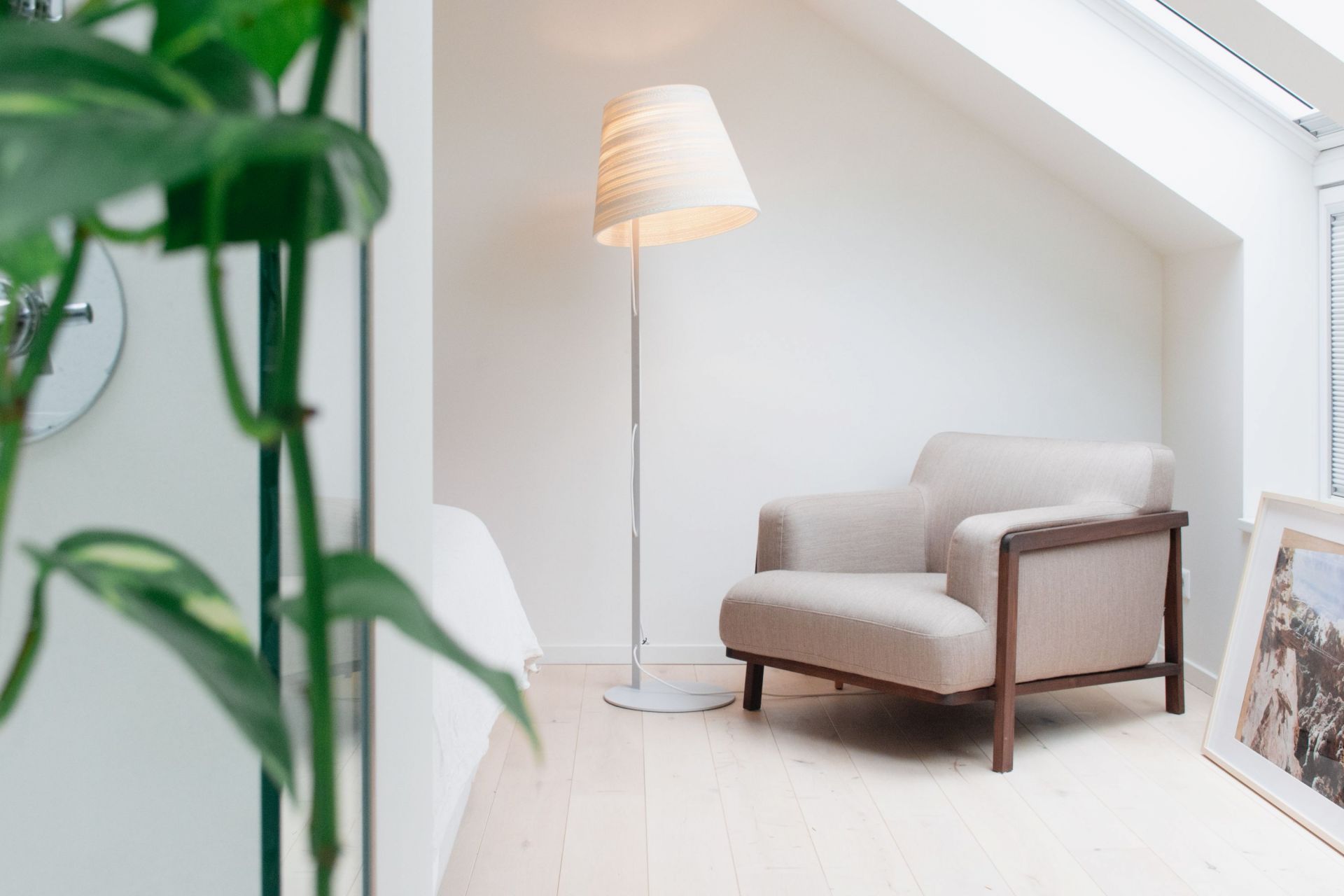 Tilt Stehleuchte Scraplights von Graypants in Weiß, neben einem Sessel in einem hellen Dachzimmer.