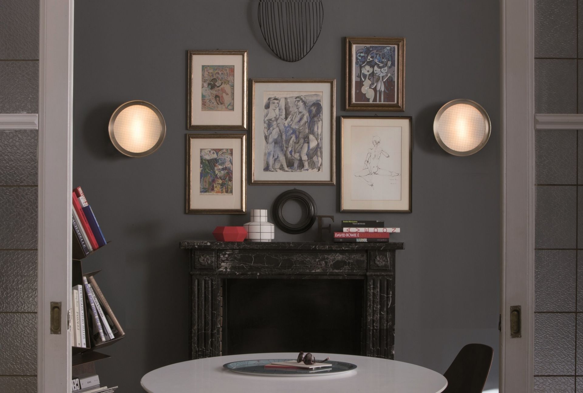 Zwei runde Berlin Wandleuchten von Oluce an grauer Wand mit Kunst und Kamin.